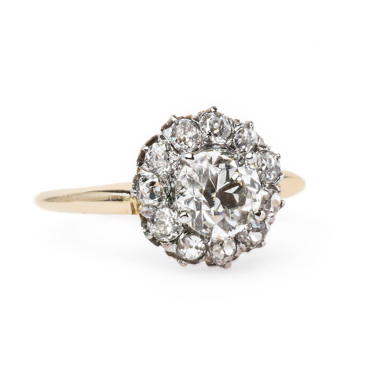 Sardinia is an incredible Victorian era (circa 1895) platinum-topped 18k yellow gold cluster ring centering a four-prong set EGL certified 1.04ct Old European Cut diamond graded J color and SI2 clarity. This antique beauty is further accented with a