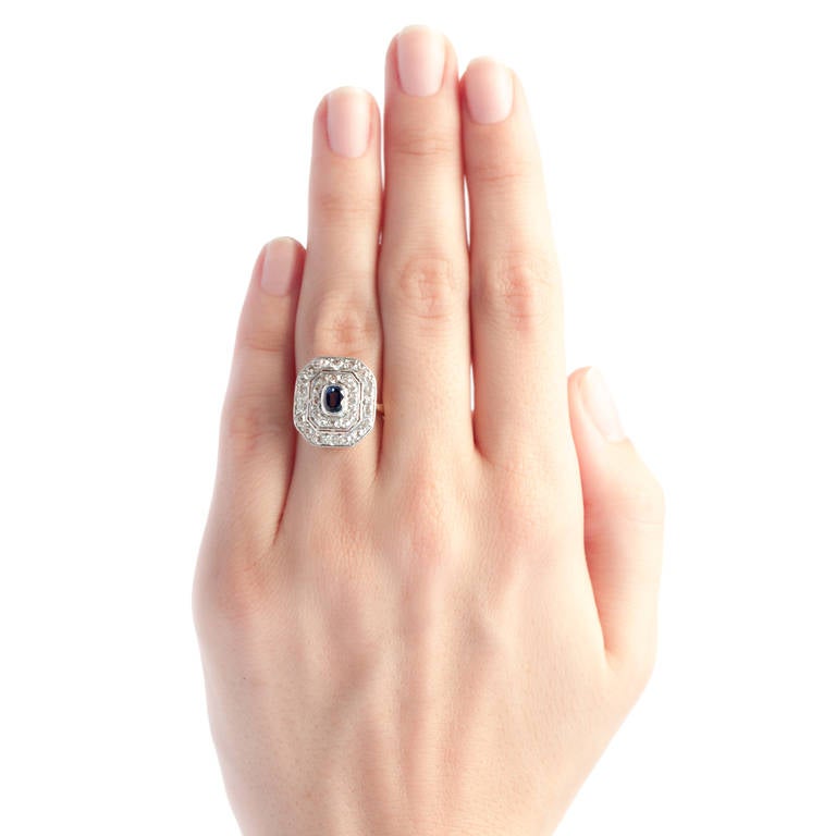 Fisher Island is an elegant Edwardian era ring made from platinum topped 14k yellow gold, starring a pretty natural sapphire gauged at 0.35ct with a lovely moderate purplish blue hue. This gorgeous sapphire is surrounded by two octagonal diamond