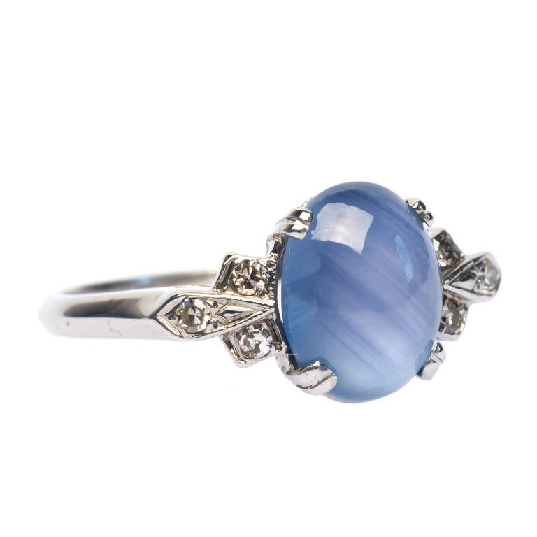 Orchard Hill is a classic Late Art Deco 14k white gold ring centering an oval 2.70ct cabochon sapphire, cool in tone, displaying very subtle asterism and flanked on either side by six single cut diamonds in a fan shaped motif totaling approximately