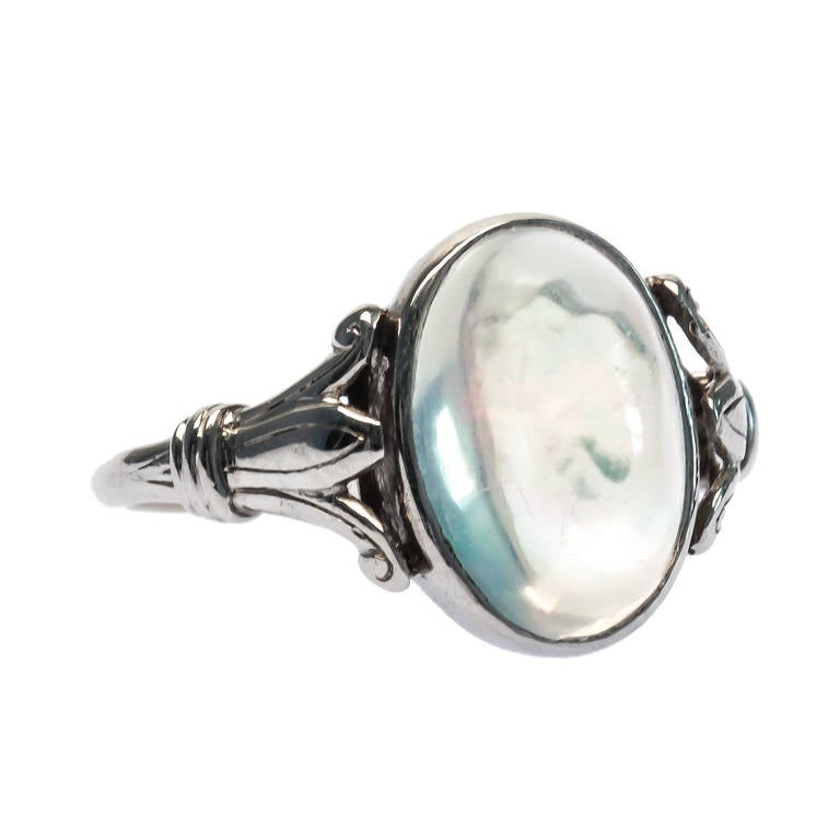 Willowbrook is a dreamy Edwardian era platinum ring centering a beautiful bezel set 2.51ct transparent oval opal displaying subtle red, green and orange play-of-color. Willowbrook's platinum mounting has a lovely triple split shank and is adorned