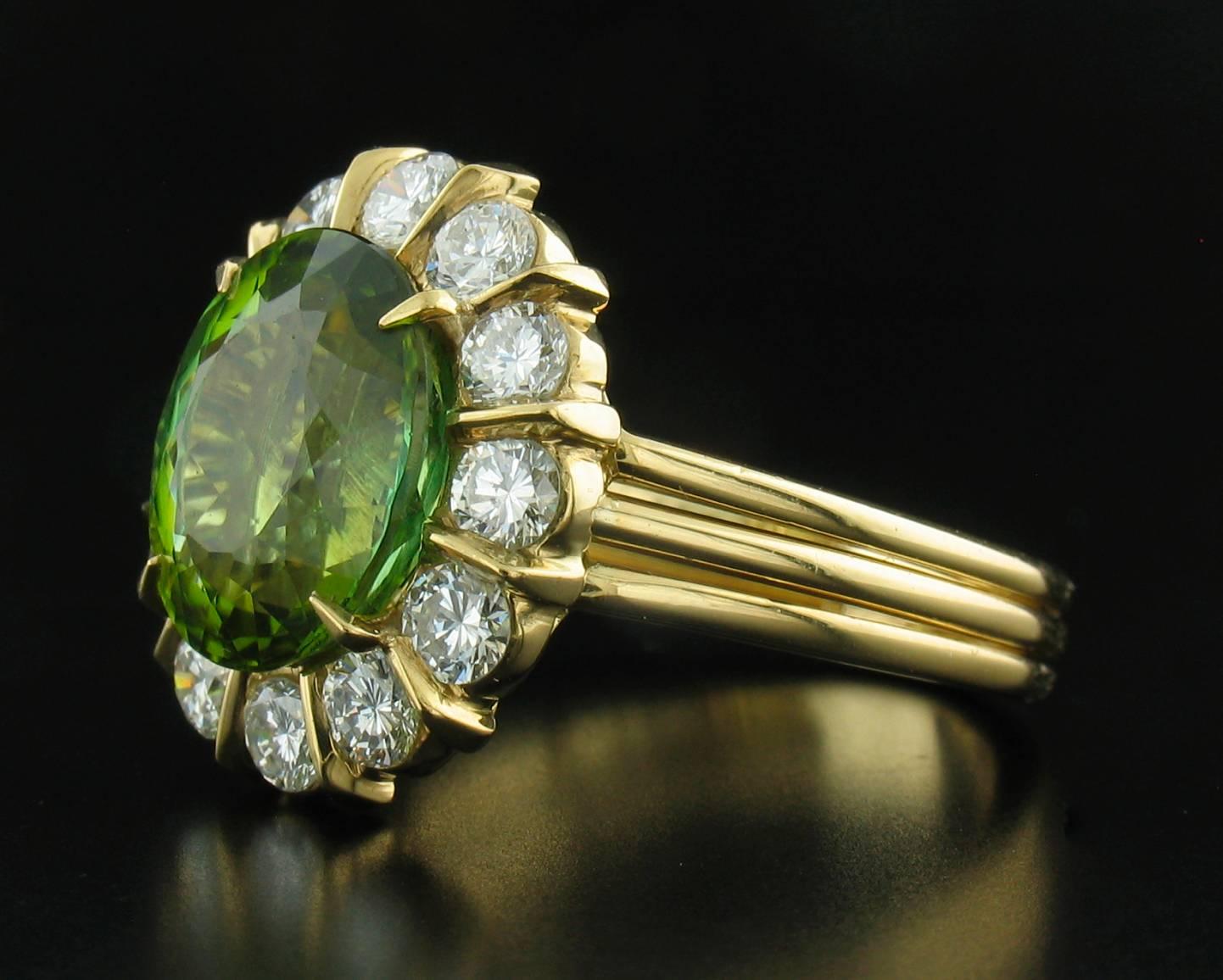A single oval Green Tourmaline weighing 5.19 carats is surrounded by 12 high quality Diamonds weighing 1.30 carats total in this classic 18k yellow gold setting.  It is a size 6 1/2, but can easily be sized.  Stamped 18k and unknown hallmark. 