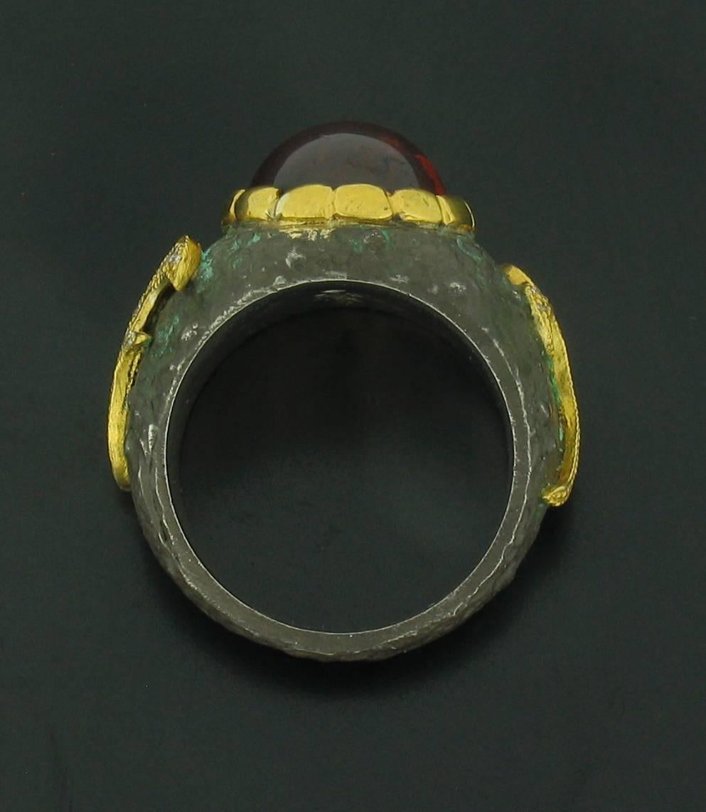 This ring was designed and made by well known designer Victor Veylan. It contains a beautiful warm toned, red-orange oval cabochon Spessartite weighing 12.95 carats, and Diamond accents weighing 0.19 carats.  It is made of a base of pure Silver with