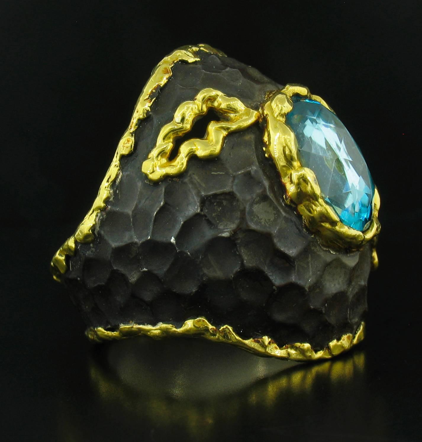 This ring was designed and made by well known designer Victor Veylan. It contains an oval faceted Blue Zircon weighing 3.97 carats.  It is made of a base of pure Silver with all accent work created in 24k yellow gold. The 'brown' is a proprietary