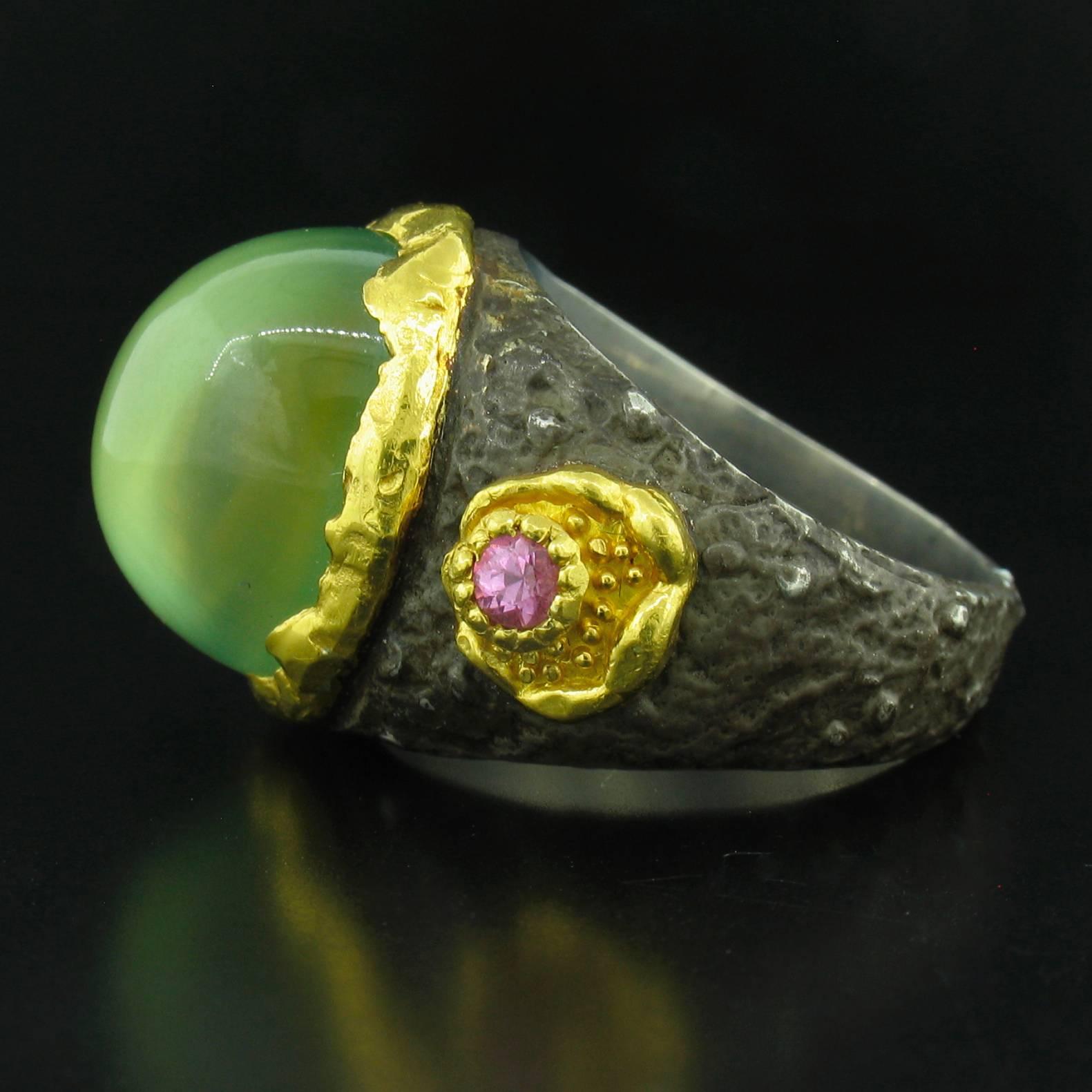 This ring was designed and made by well known designer Victor Velyan. It contains a beautiful oval cabochon Prehnite weighing 15.90 carats, and reverse set Pink Sapphire accents weighing 0.25 carats.  It is made of a base of pure Silver with all