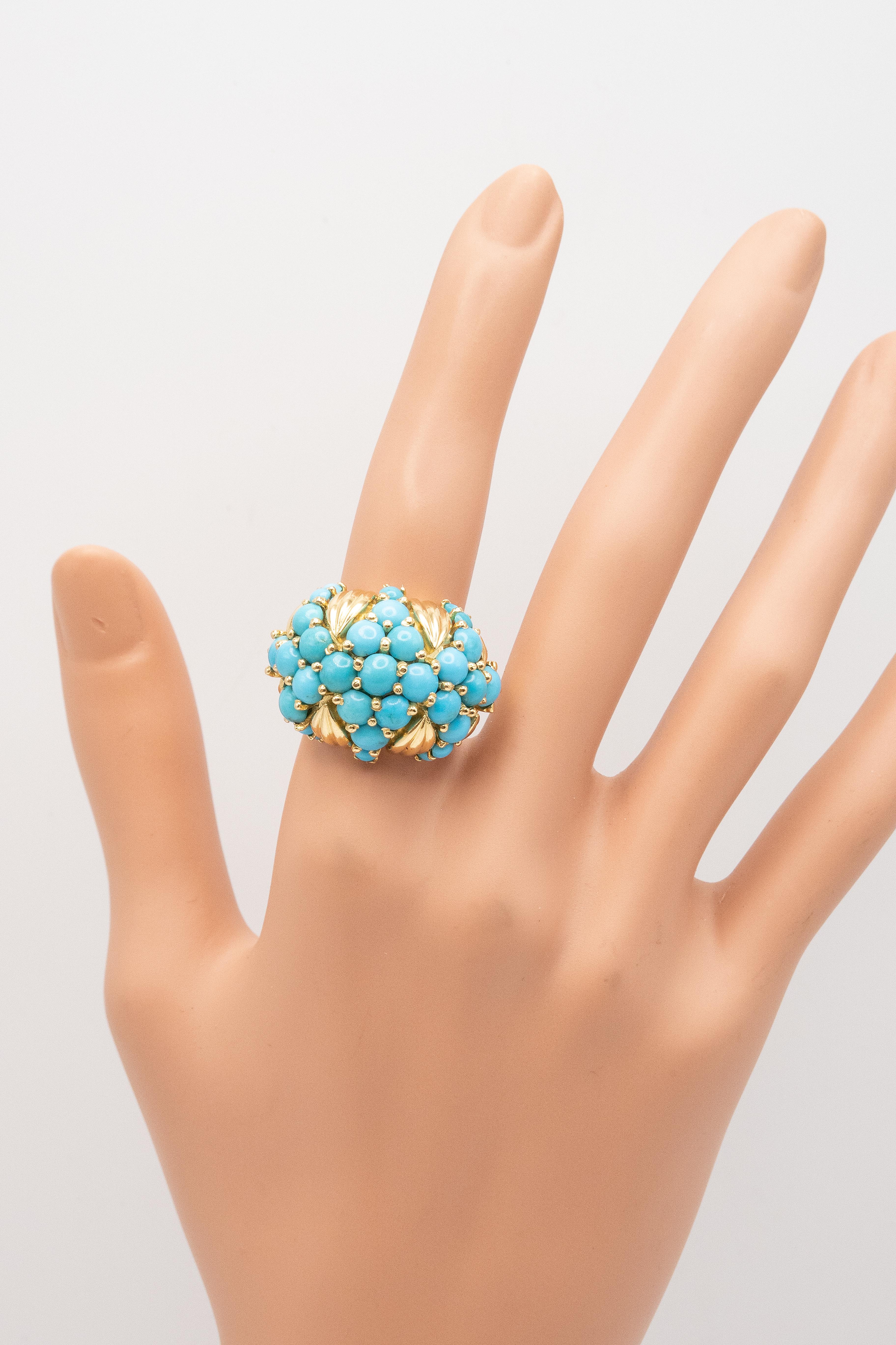 Questo splendido anello con cupola di turchese, sapientemente realizzato in oro giallo 18 carati con un gruppo di turchesi persiani cabochon incastonati in un audace design a bombe, presenta accenti scultorei in oro che incorniciano il turchese in