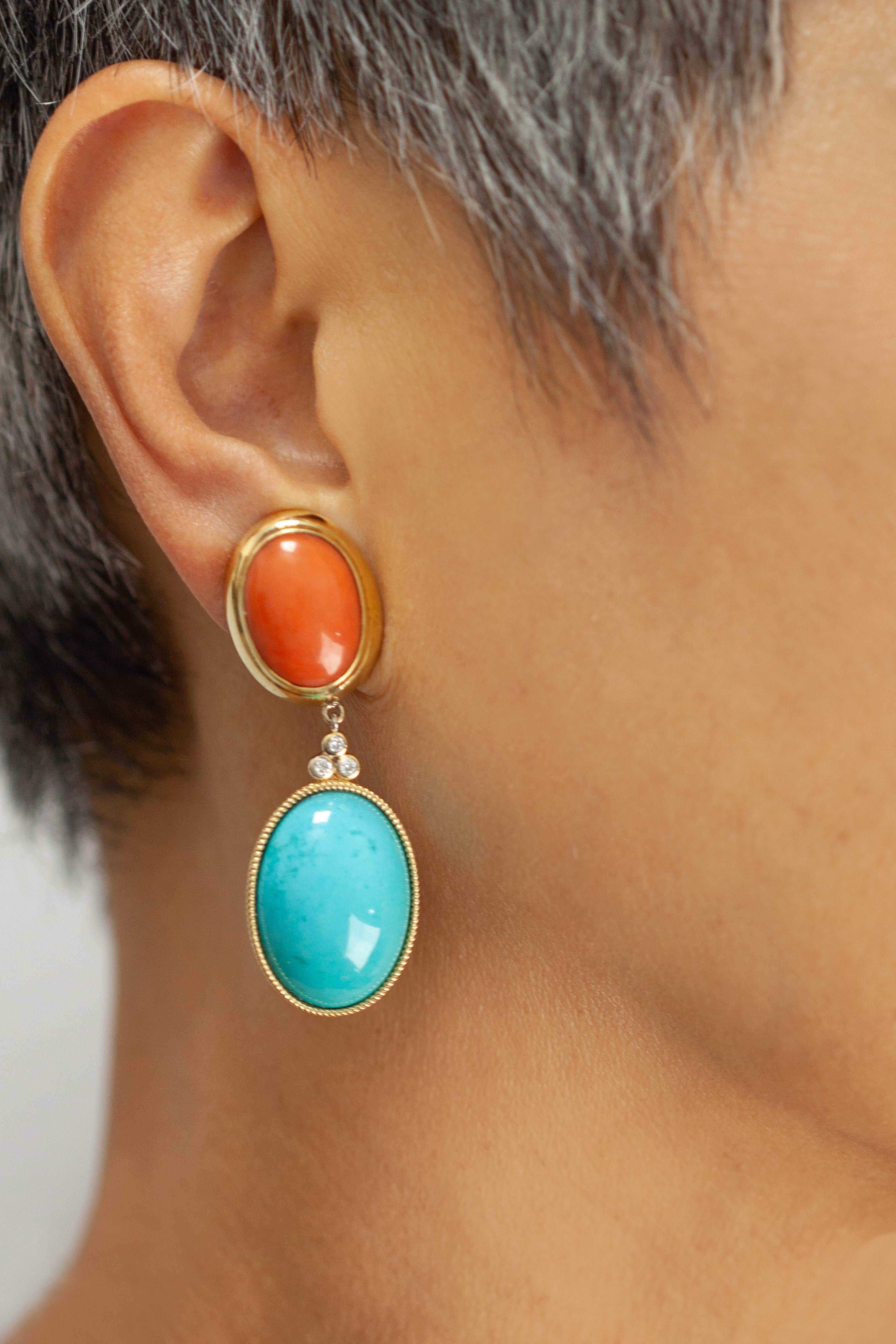 Realizzati con maestria in oro giallo 18 carati, questi eleganti orecchini pendenti a clip sono impreziositi da un vivace abbinamento di elementi naturali.  corallo rosso e cabochon di turchese. La parte superiore mostra audaci cabochon ovali di