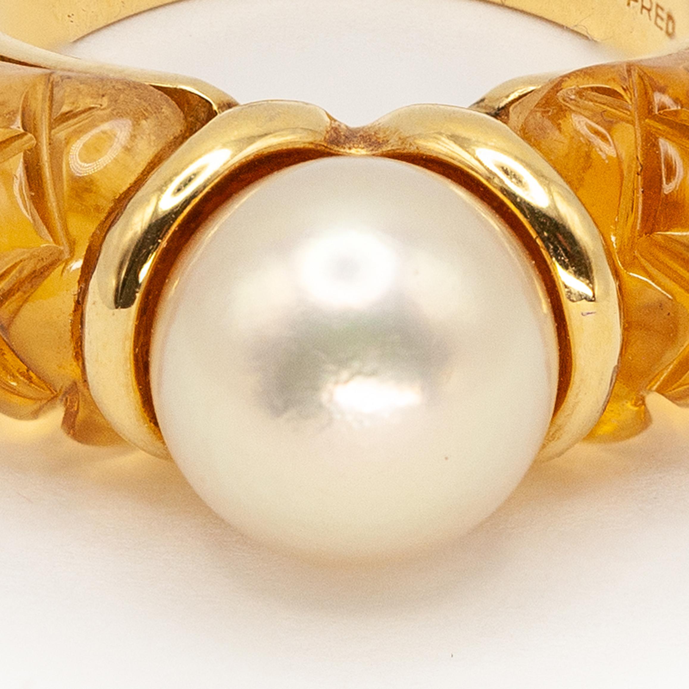 Cette bague exquise de Fred Paris est réalisée en or jaune 18 carats. Le design présente une perle de culture blanche lumineuse au centre, sertie entre deux épaules de citrines sculptées de manière complexe dans un motif matelassé. La chaude teinte