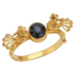 Bracciale rigido in oro giallo 18 carati con uccellino intagliato e zaffiro nero a forma di stella