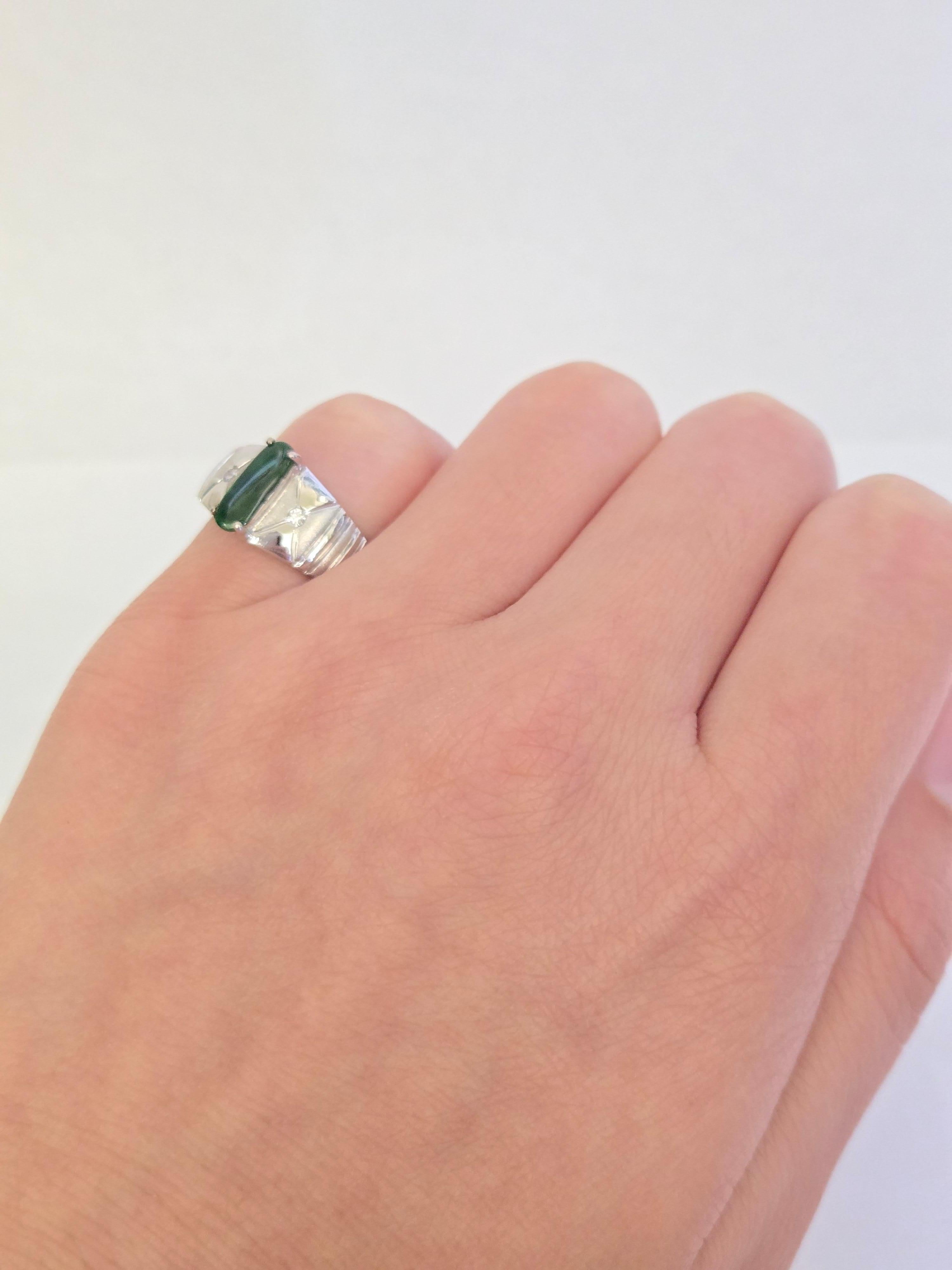 Cette bague raffinée est ornée d'un centre en jade vert naturel, rehaussé de deux petits diamants ronds. Whiting en or blanc 14K ou 18K. La taille de la bague est d'environ 3.