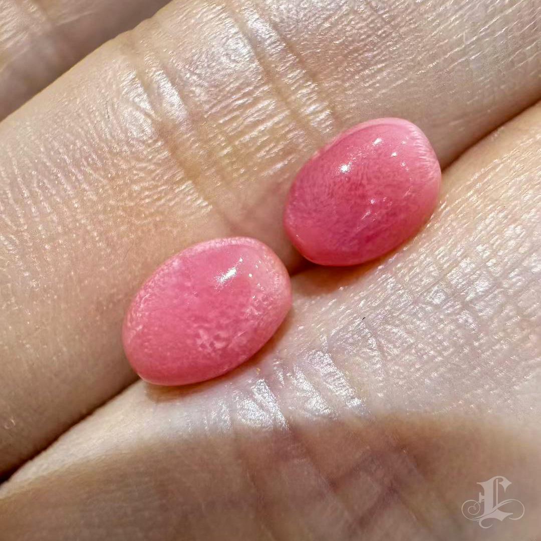 Una coppia perfettamente abbinata di perle di conchiglia naturali, caratterizzate da un'armoniosa tonalità rosa-arancio e da una radiosa struttura a fiamma visibile su entrambe le gemme. Questi rari tesori, che pesano rispettivamente 1,32 e 1,48