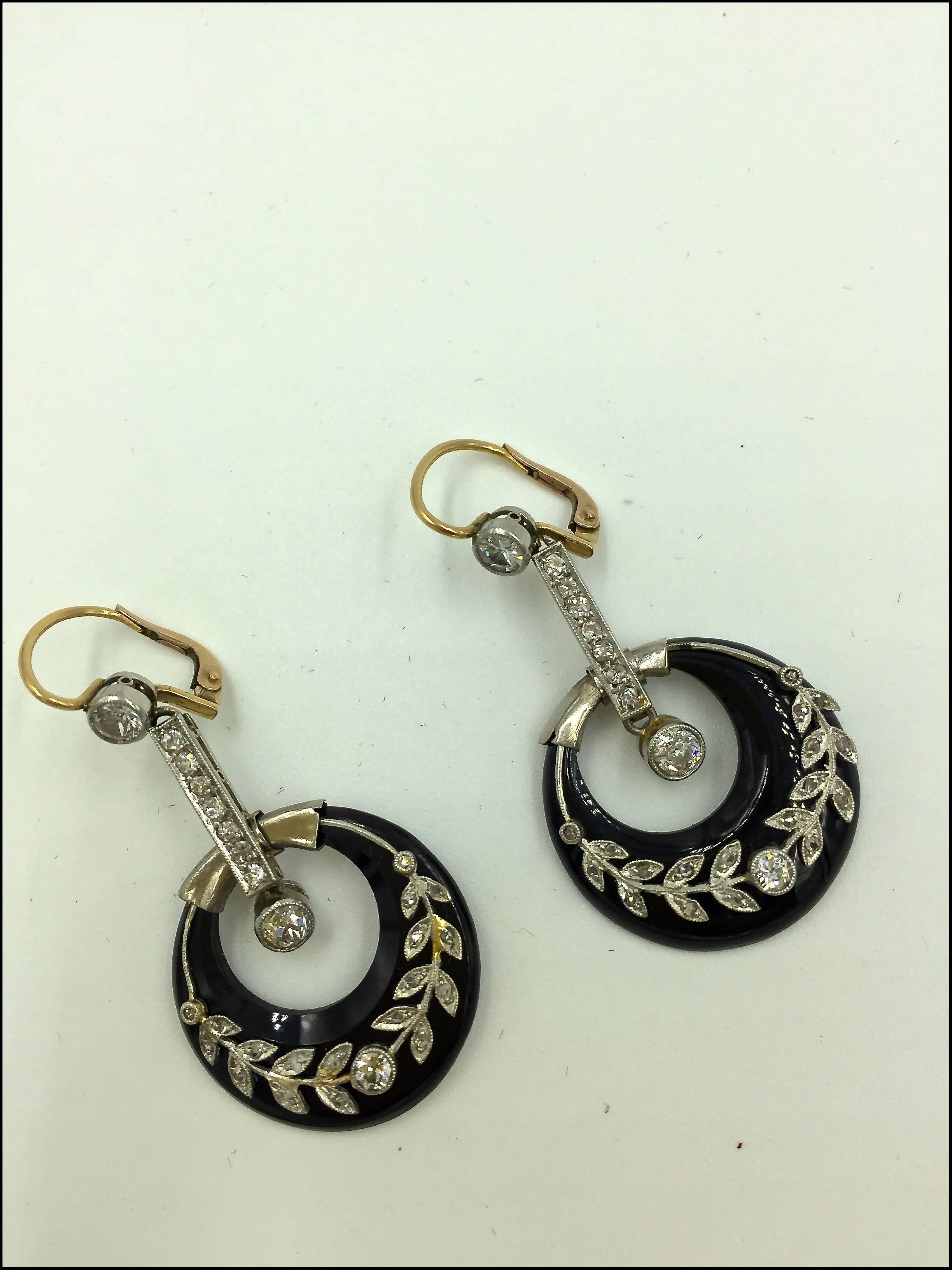 A pair of diamond and onyx drop earrings, with each earring consisting of 10 old cut diamonds and 18 rose cut diamonds set on a platinum wreath applied to an onyx crescent and with 18ct yellow gold wire French clips. 