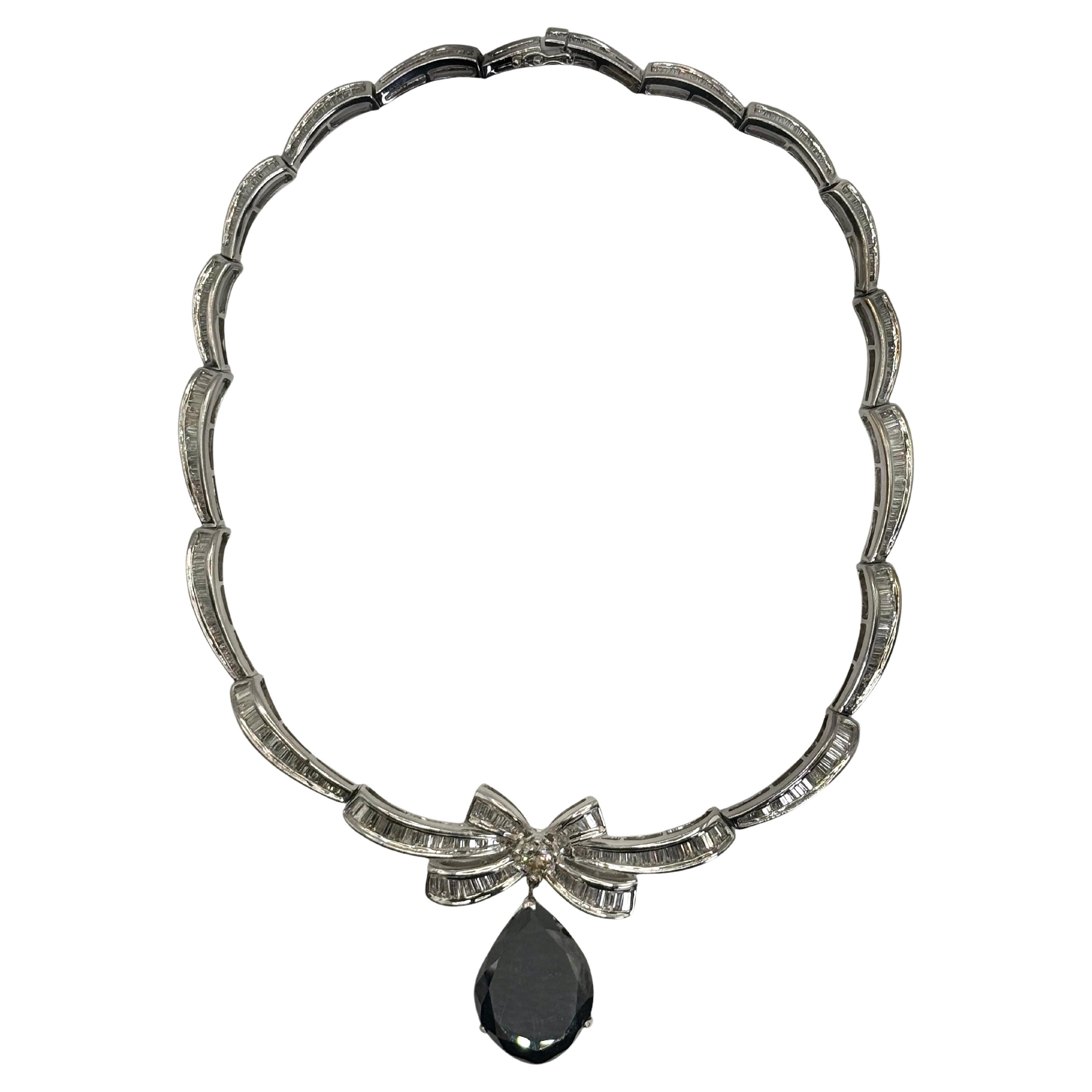 A breathtaking statement piece crafted in 18K white gold, this vintage-inspired necklace features a striking 36.78-carat pear-shaped black diamond drop, suspended from a bow motif set with round and baguette-cut diamonds. The bow centerpiece holds a