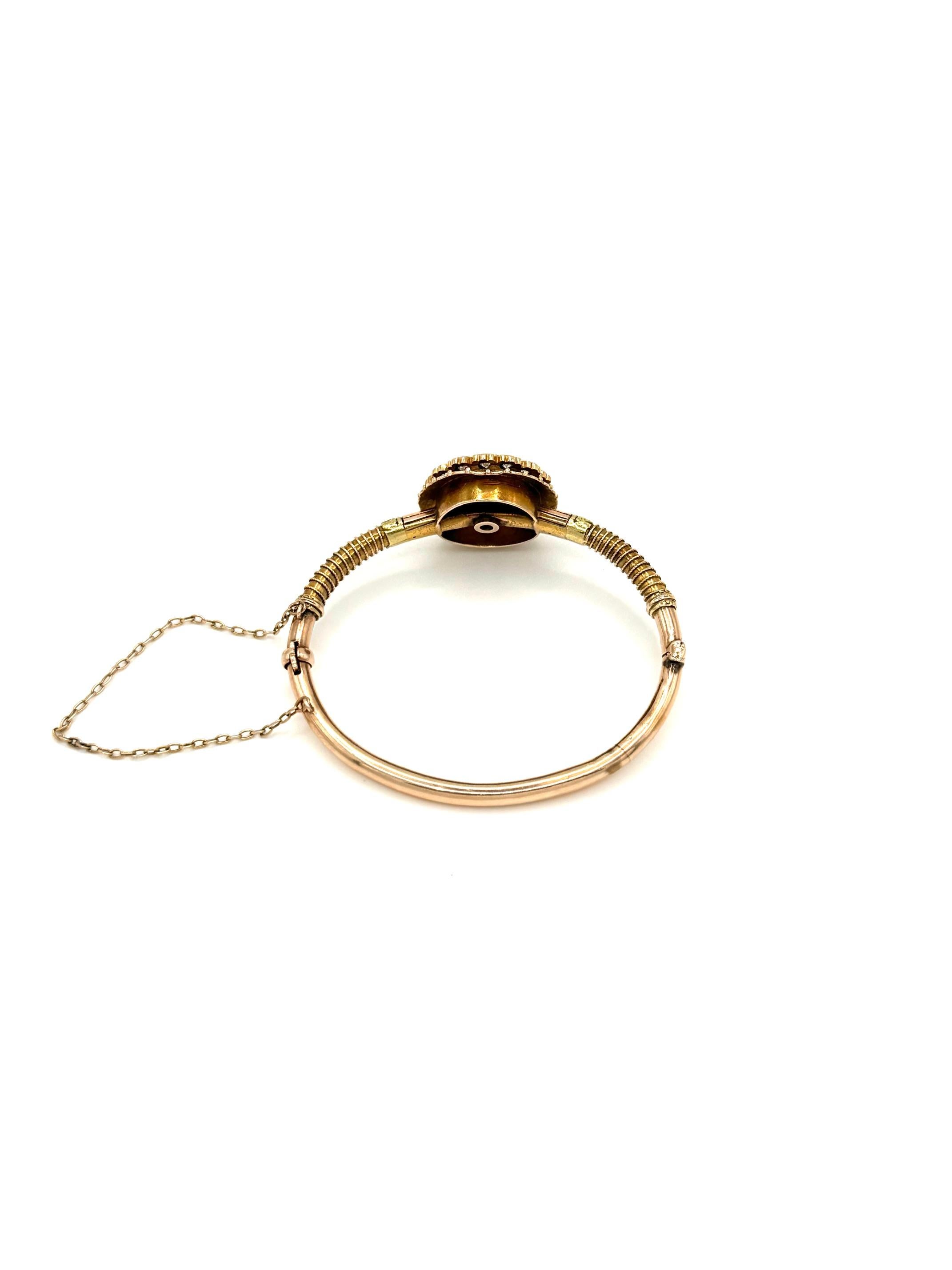 A beautifully crafted 14K yellow gold bangle bracelet featuring a bold circular centerpiece. At the center is a bezel-set square-cut diamond, framed by a double halo of brilliant-cut white diamonds arranged in a scalloped, floral-style border. The