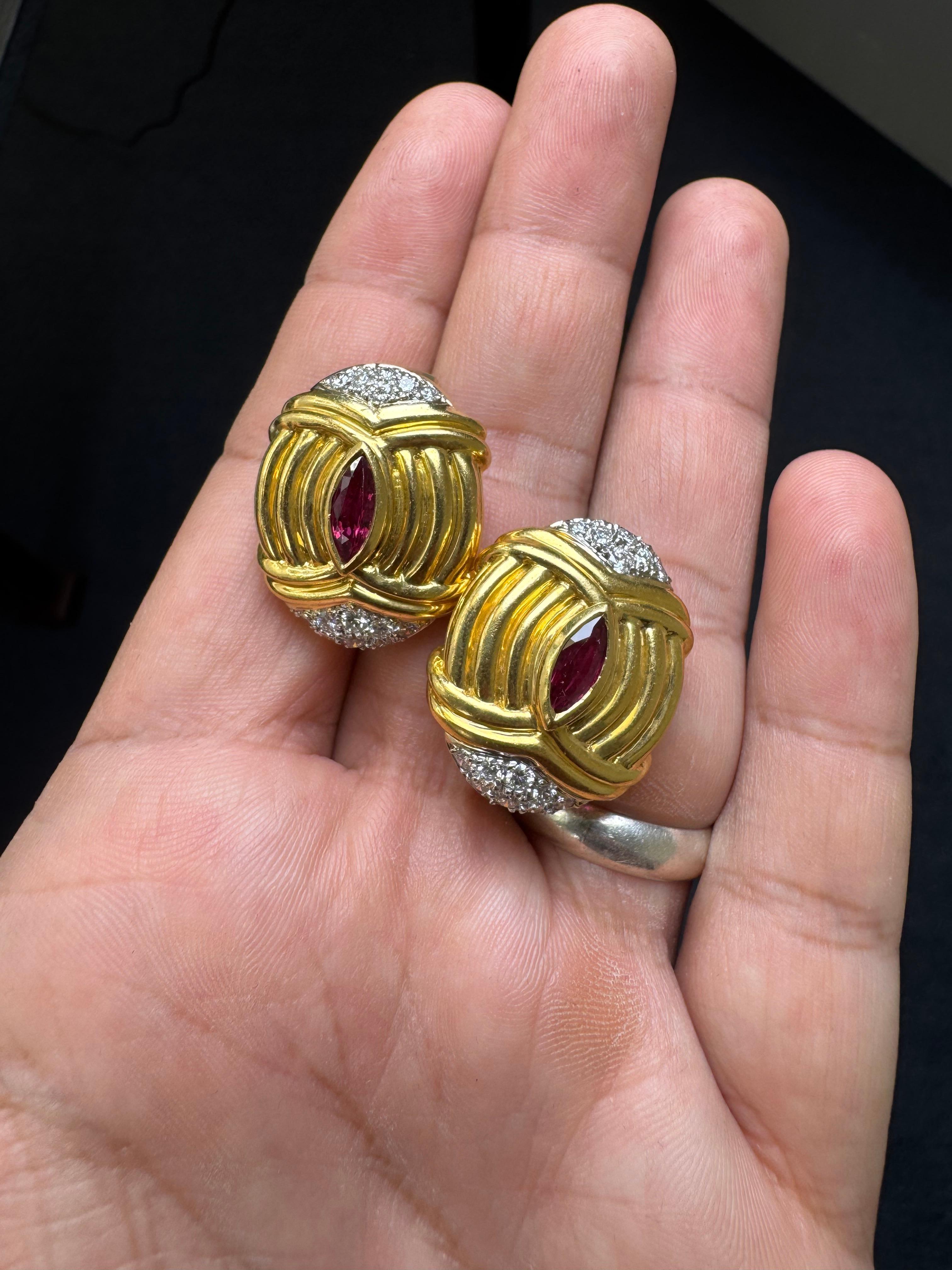 Un sorprendente paio di orecchini a clip vintage realizzati in ricco oro giallo 18 carati, con un audace design a coste centrato da vivaci rubini taglio marquise per un totale di circa 1,10 carati. Ogni orecchino è impreziosito da diamanti taglio