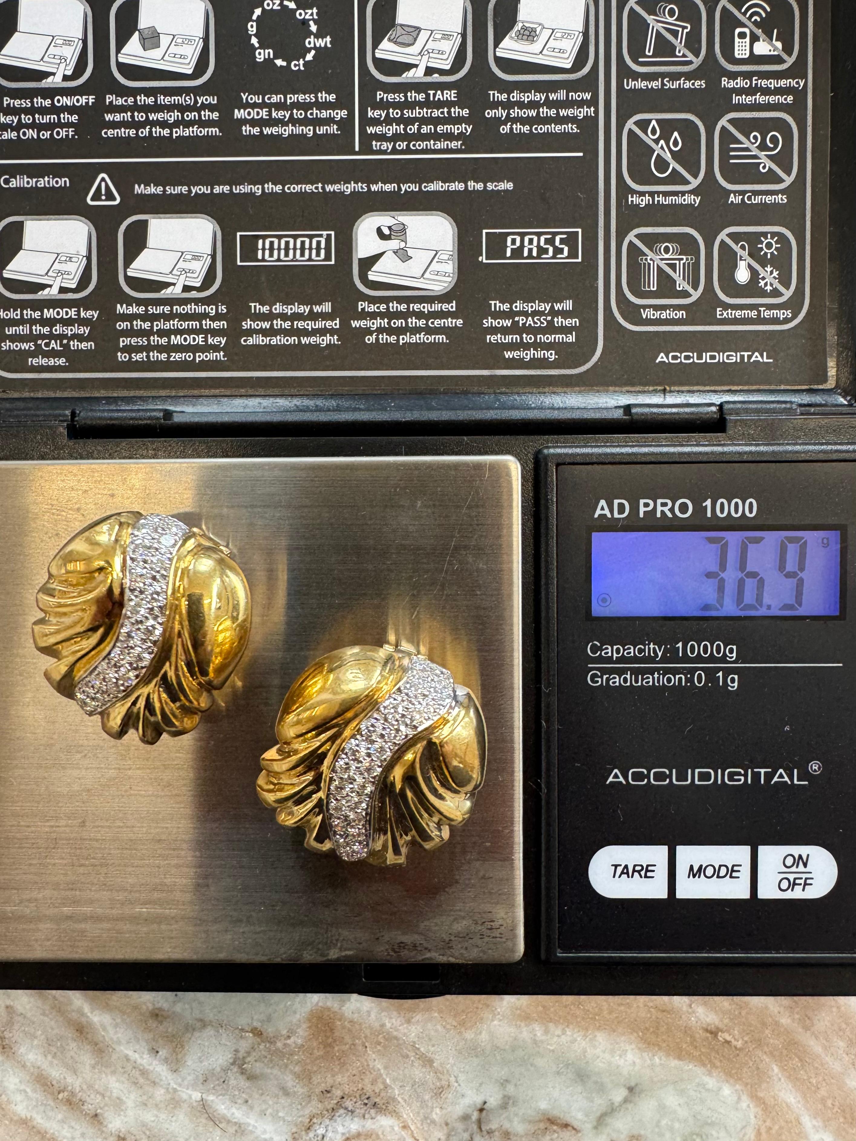 Un sorprendente paio di orecchini vintage con motivo a spirale realizzati in ricco oro giallo 18 carati, accentuato da una graziosa curva a S di diamanti taglio brillante incastonati in oro bianco. Il design dimensionale presenta scanalature
