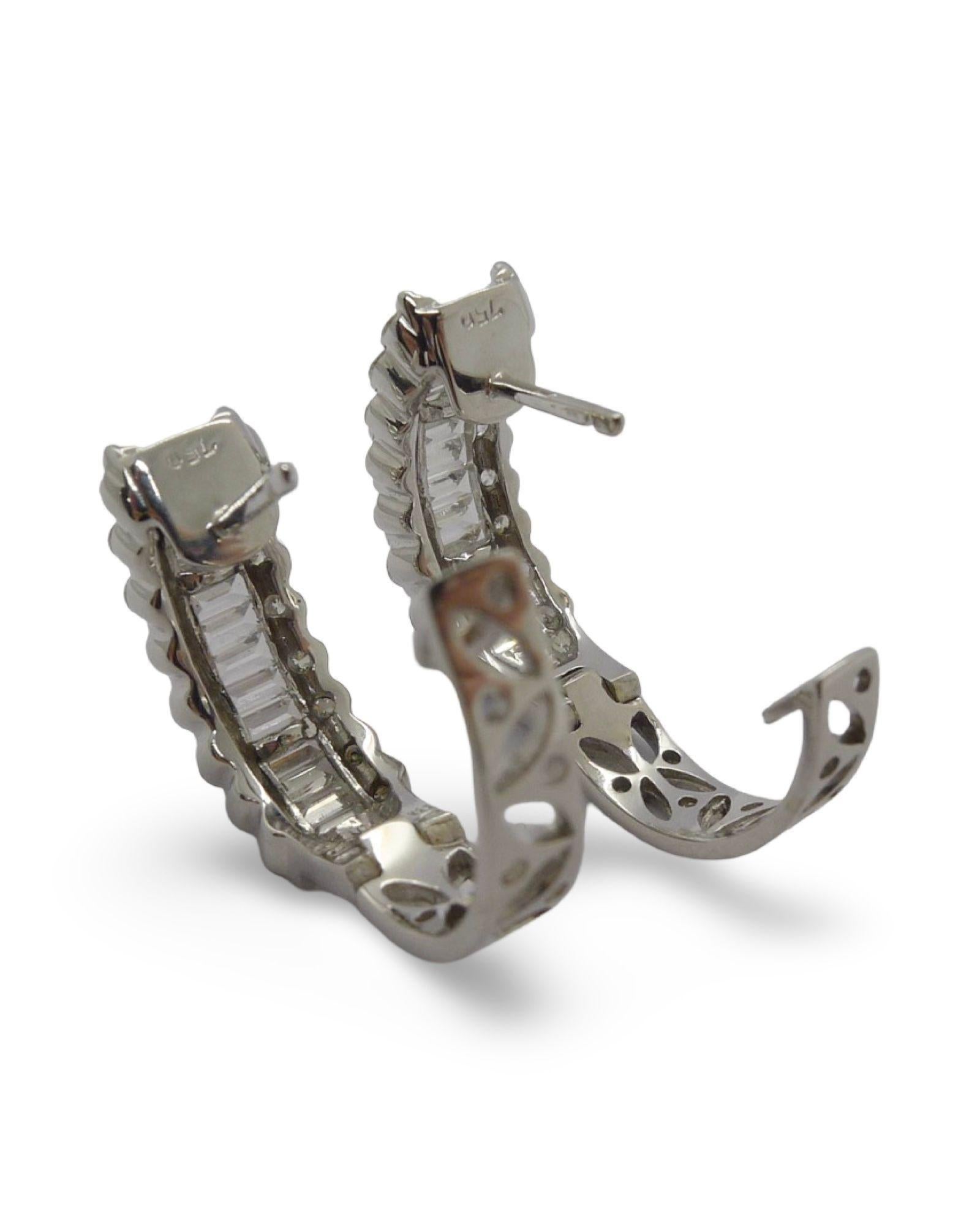 Questi lussuosi orecchini sono realizzati in oro bianco 18 carati di alta qualità (750/1000) e impreziositi da un'abbagliante selezione di diamanti naturali. Il design è caratterizzato da diamanti con taglio a brillante e a baguette, meticolosamente