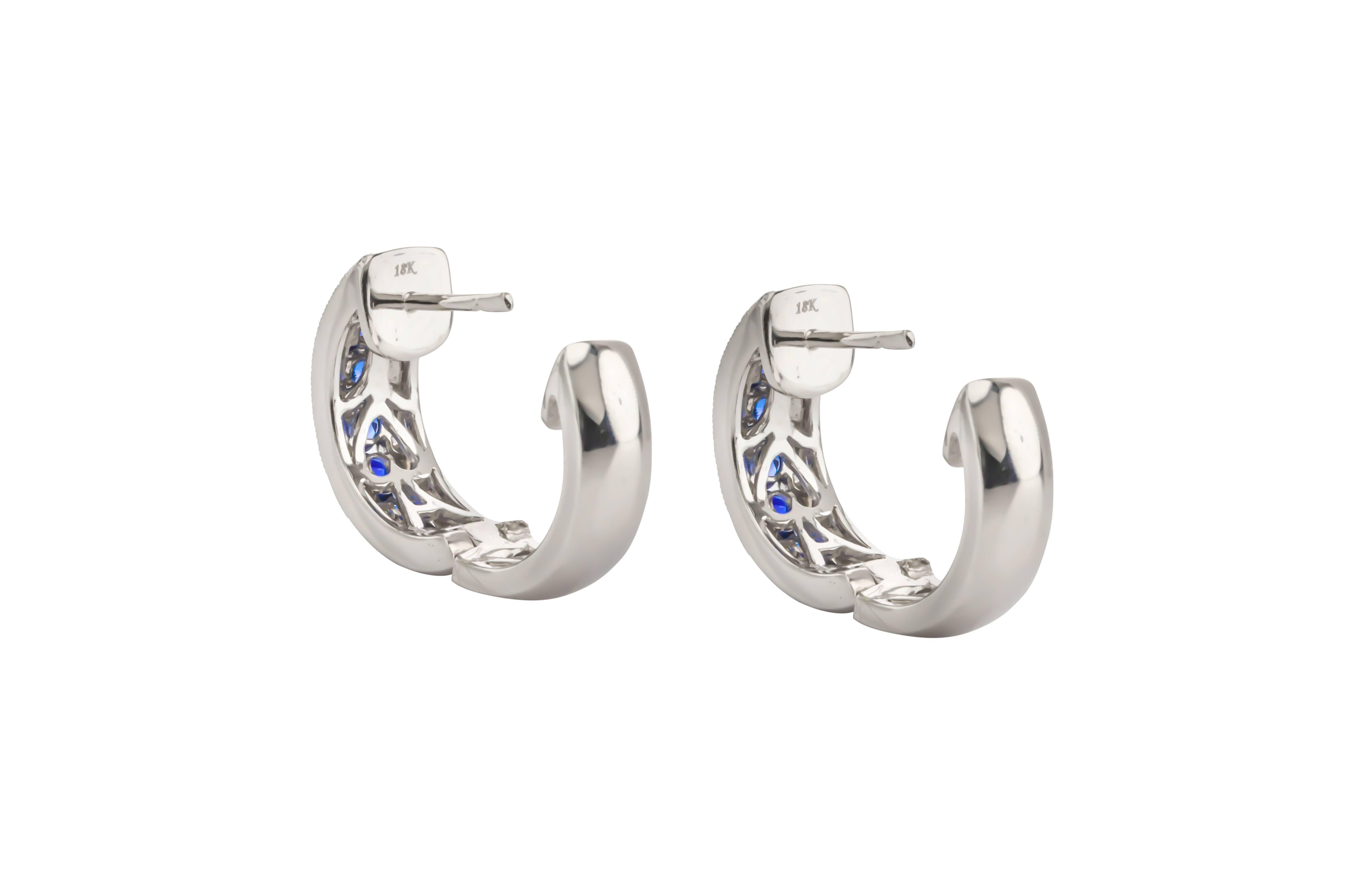 18K white gold blue sapphire and diamond hoop earrings. Set with blue sapphires weighing 1.68 carats total weight of fine color and clarity, surrounded in a scalloped design of round brilliant cut diamonds weighing .18 carats total weight, F-G color