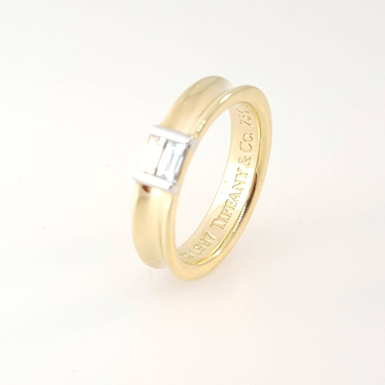 Tiffany & Co. 18 karat yellow gold ring set with 2 Baguette cut diamonds. The diamonds are bar set and weigh 0.25cttw. The ring is stamped on the inside 1997 Tiffany & Co. 750. The ring is a size 6 and is not resizable.