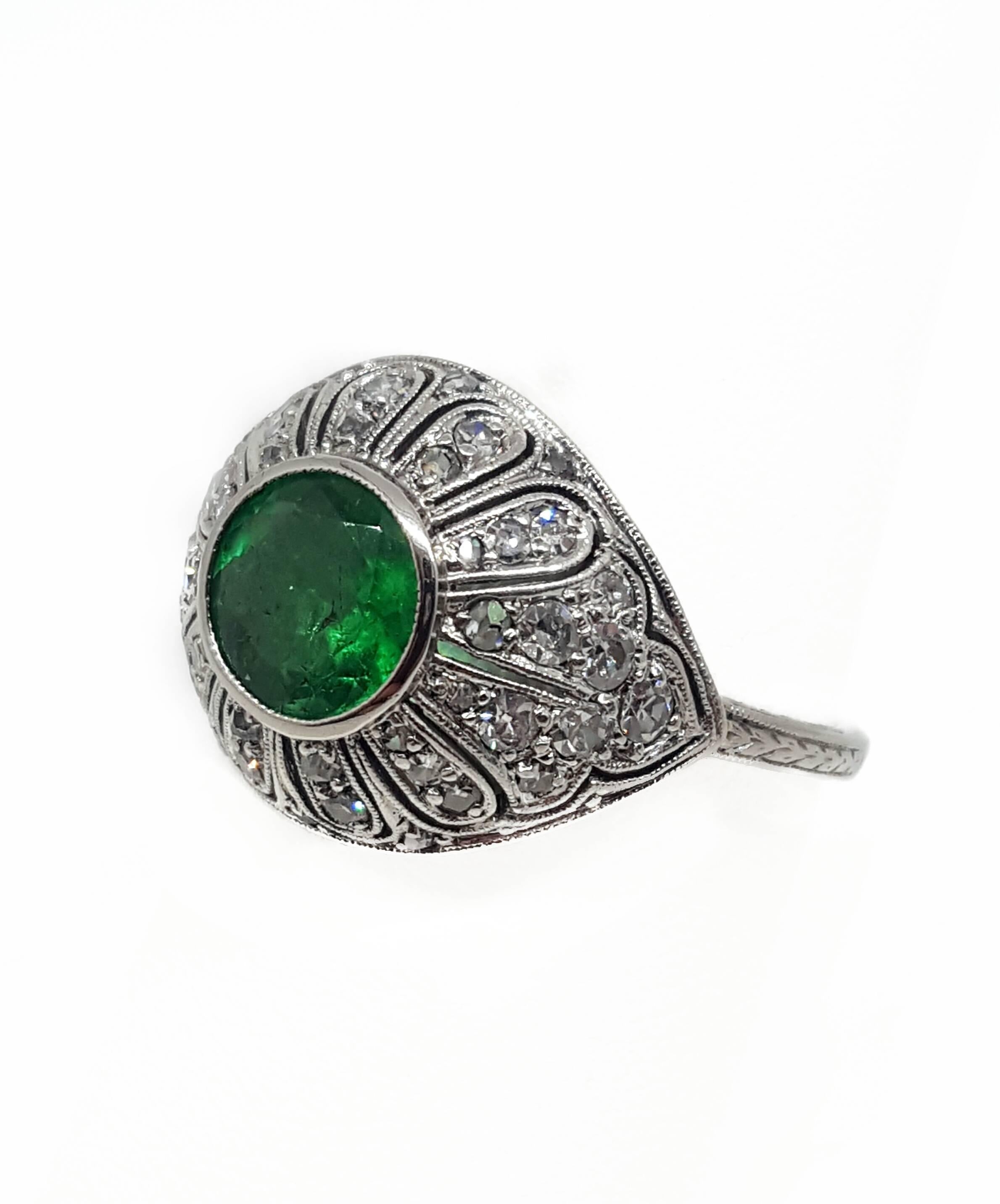 A platinum ring set with 40 round cut diamonds and 1 round cut emerald. The emerald weighs approximately 1.40 carats and is a fine medium light green color. The diamonds are VS2 to SI1 clarity and weigh approximately 0.50 carats total weight. The