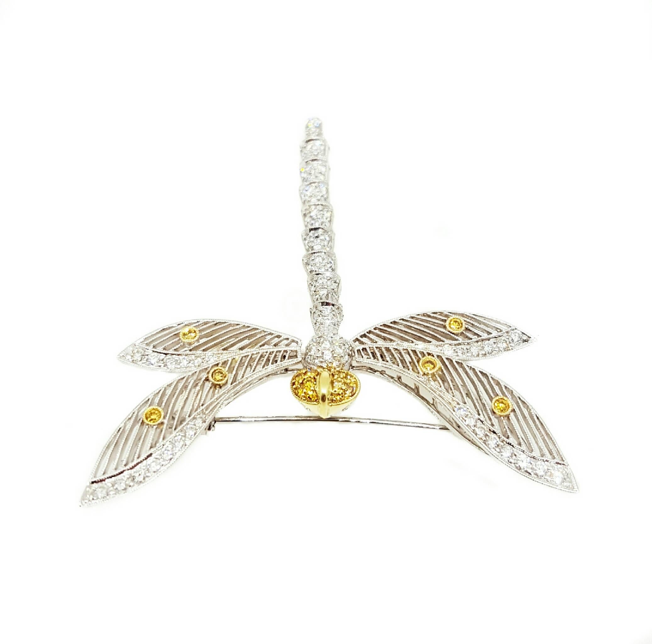 An 18 karat white gold Dragonfly pin set with 101 Round Brilliant cut white diamonds that weigh exactly 1.05 carats total weight and 16 Fancy Yellow diamonds that weigh exactly 0.21 carats total weight. The tail is "en tremblant". The pin