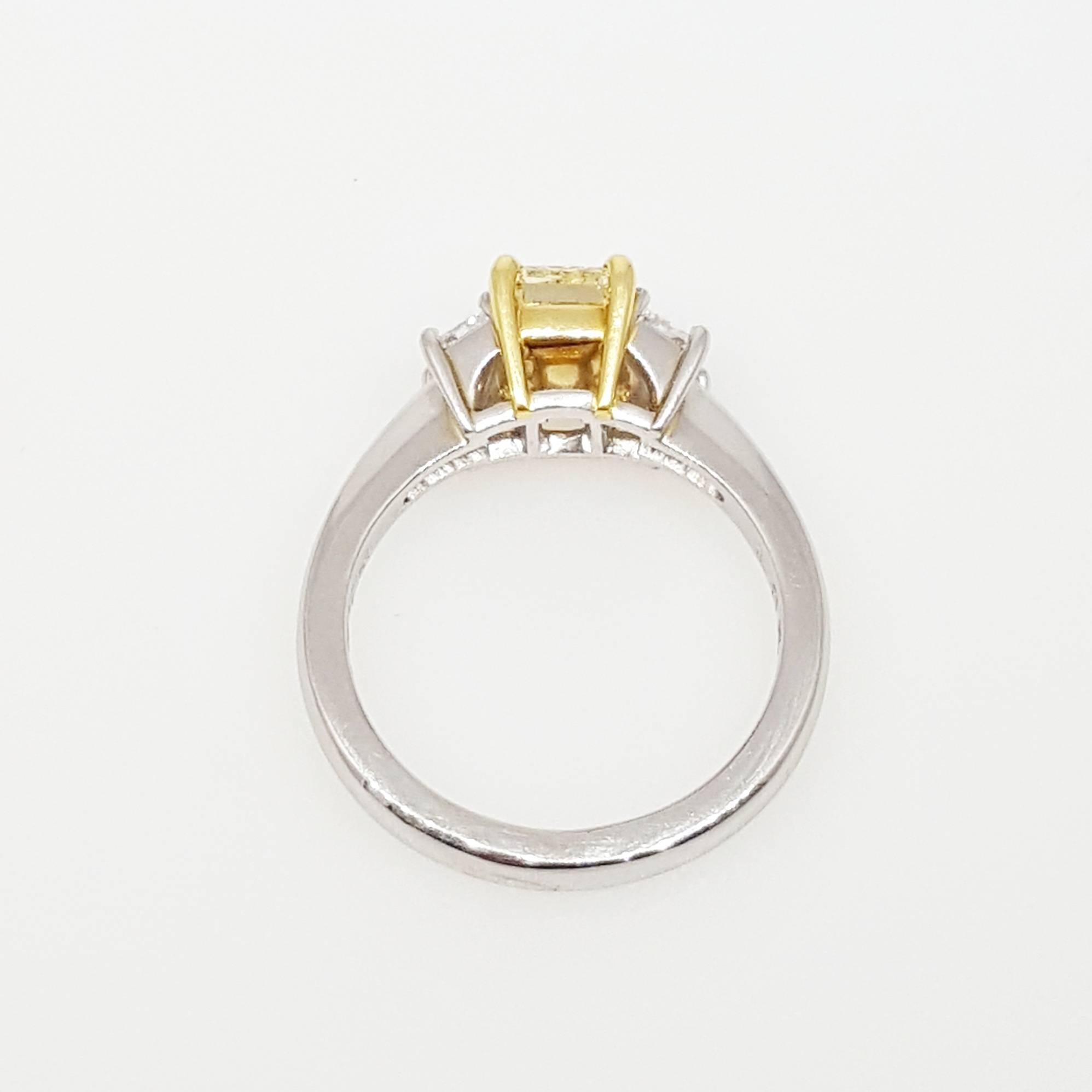 Platinum and 18 karat yellow gold ring set with a 1.51 carat Fancy Light Yellow VS1 Clarity (GIA certified) Cut-Cornered Rectangular Modified Brilliant diamond in the center and two white trapezoid cut diamonds on the side that weigh 0.66cttw and