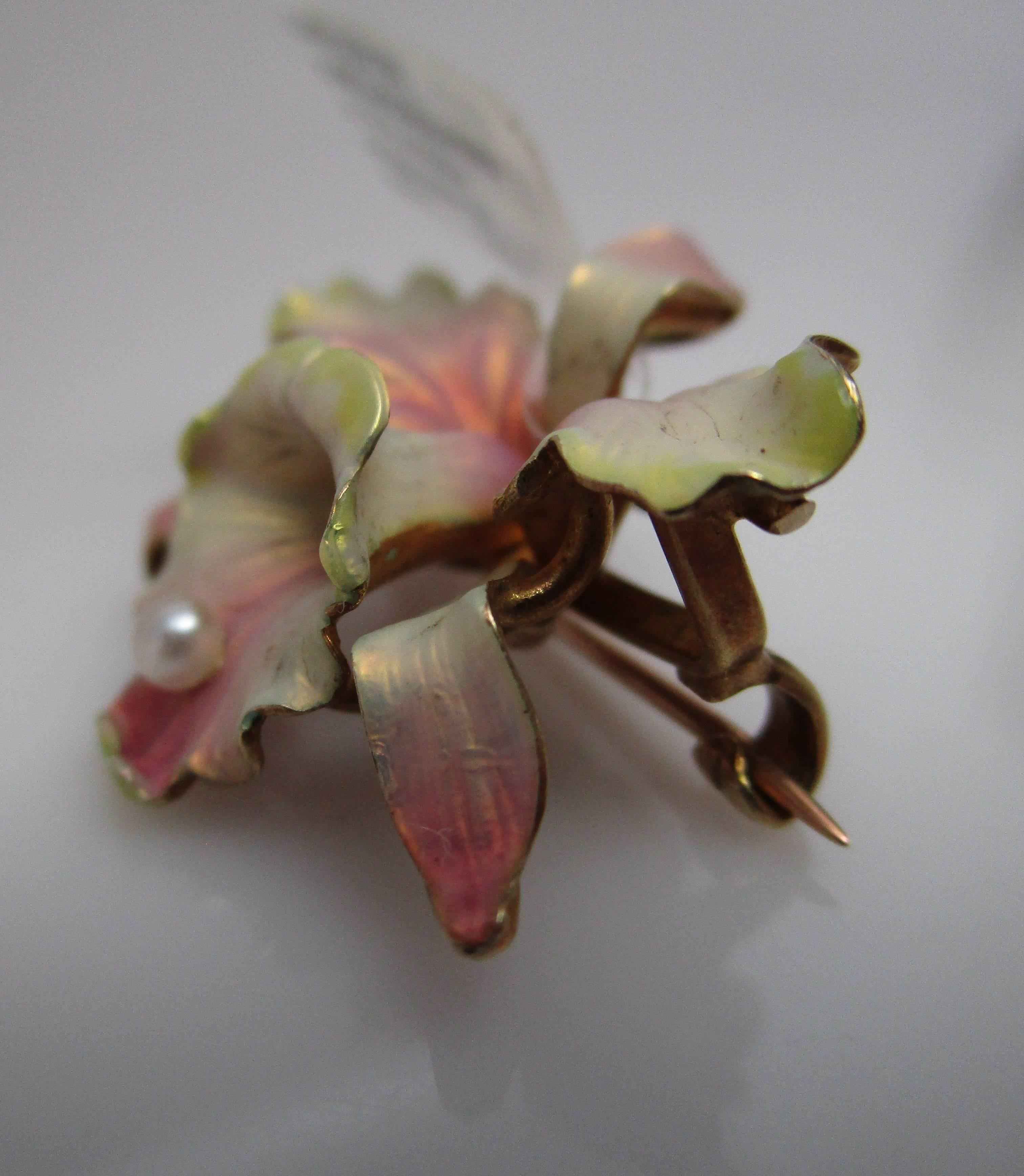 Con una delicada floritura, este broche de orquídea pasa del magenta translúcido al oliva en los delicados pétalos aterciopelados. Las líneas son tan fluidas que parece que pudiera tratarse de una orquídea de verdad. Este broche data de alrededor de