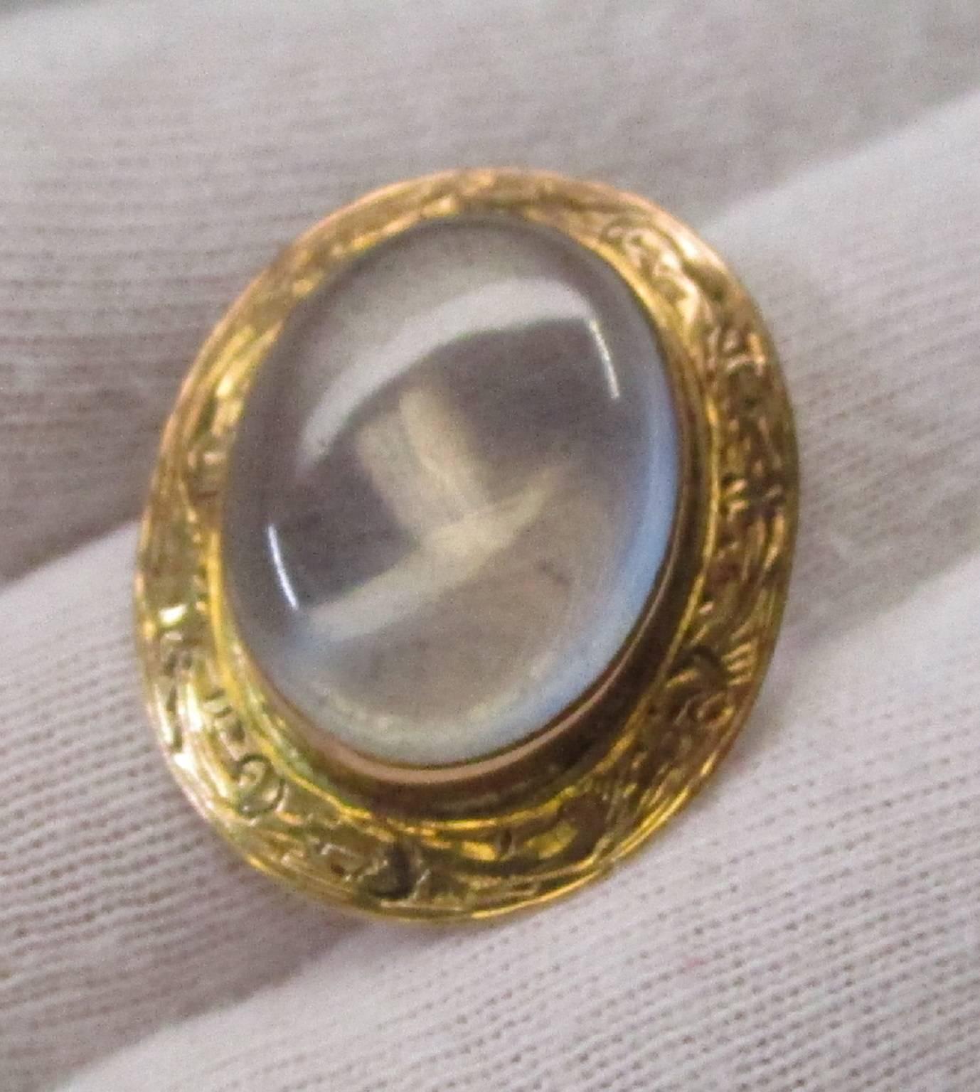 This pin from the late Victorian era is opulent and magnificent. It is 10 karat gold, which holds a luscious moonstone in a warm embrace. The golden scroll work is hand-engraved, which is precise and sharp and has aged very well. The exquisite