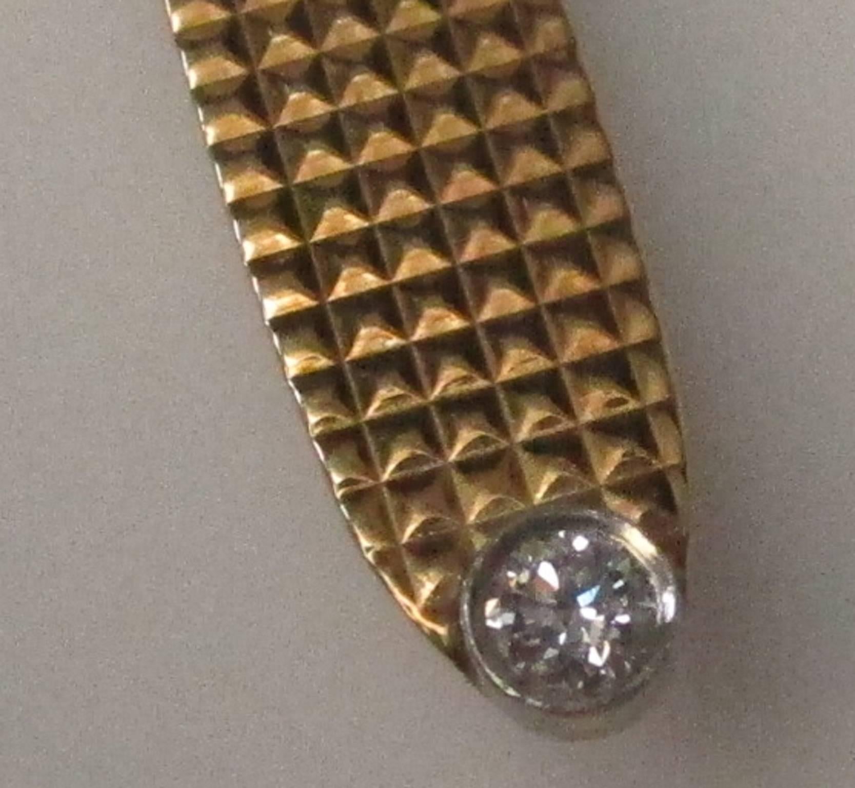 This is a Tiffany and Co. tie clip made of patterned 14K yellow gold with a brilliant 0.10ct diamond, H color and VS1 clarity, in a platinum bezel. No self respecting man wants his tie flapping around, might as well look good with this exquisite tie