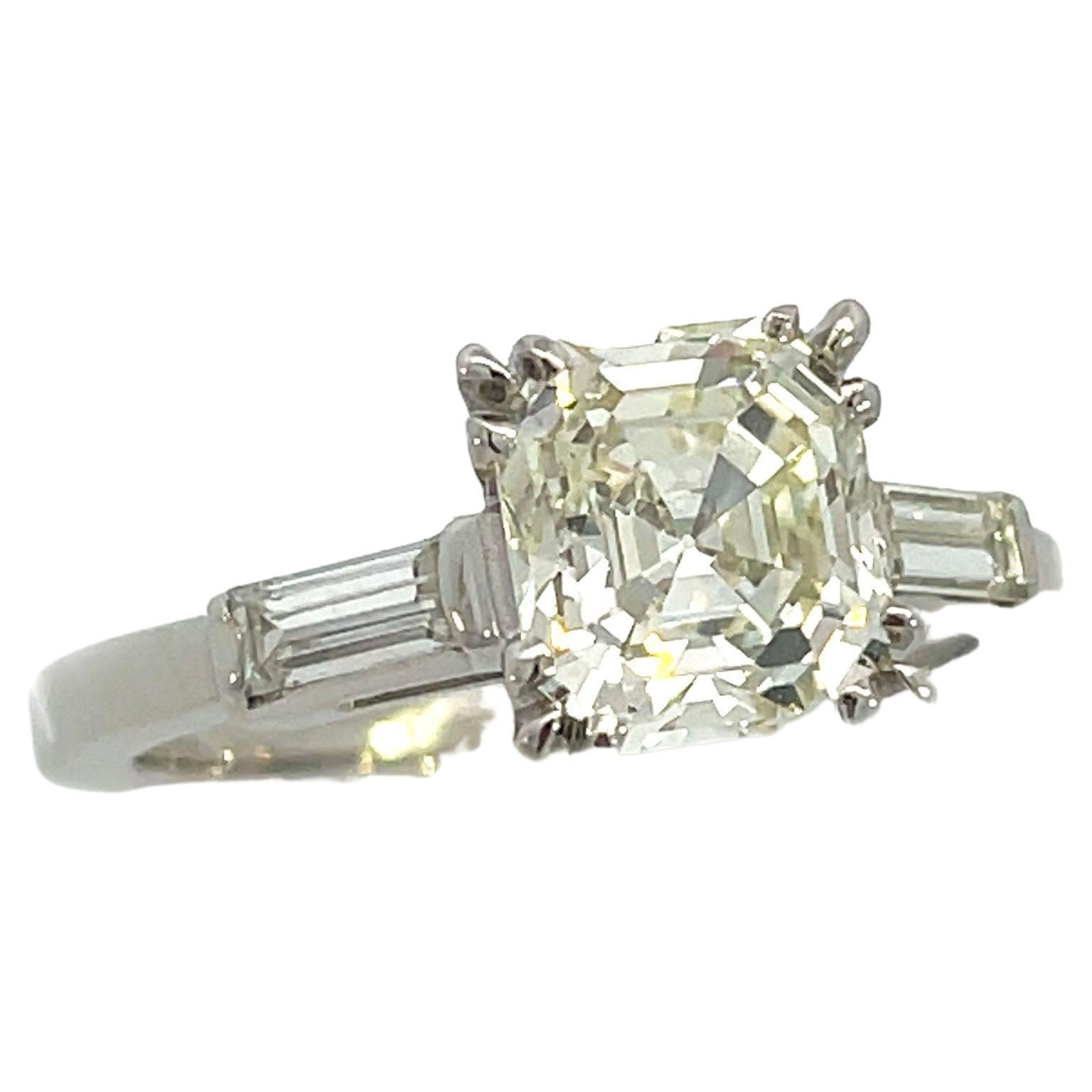 This is an outstanding Art Deco engagement ring crafted in Platinum that showcases a jaw-dropping 1.84-carat Asscher cut diamond. A dazzling Asscher-cut, weighing 1.84 carats, radiates between a pair of gleaming baguette diamonds, in this simply