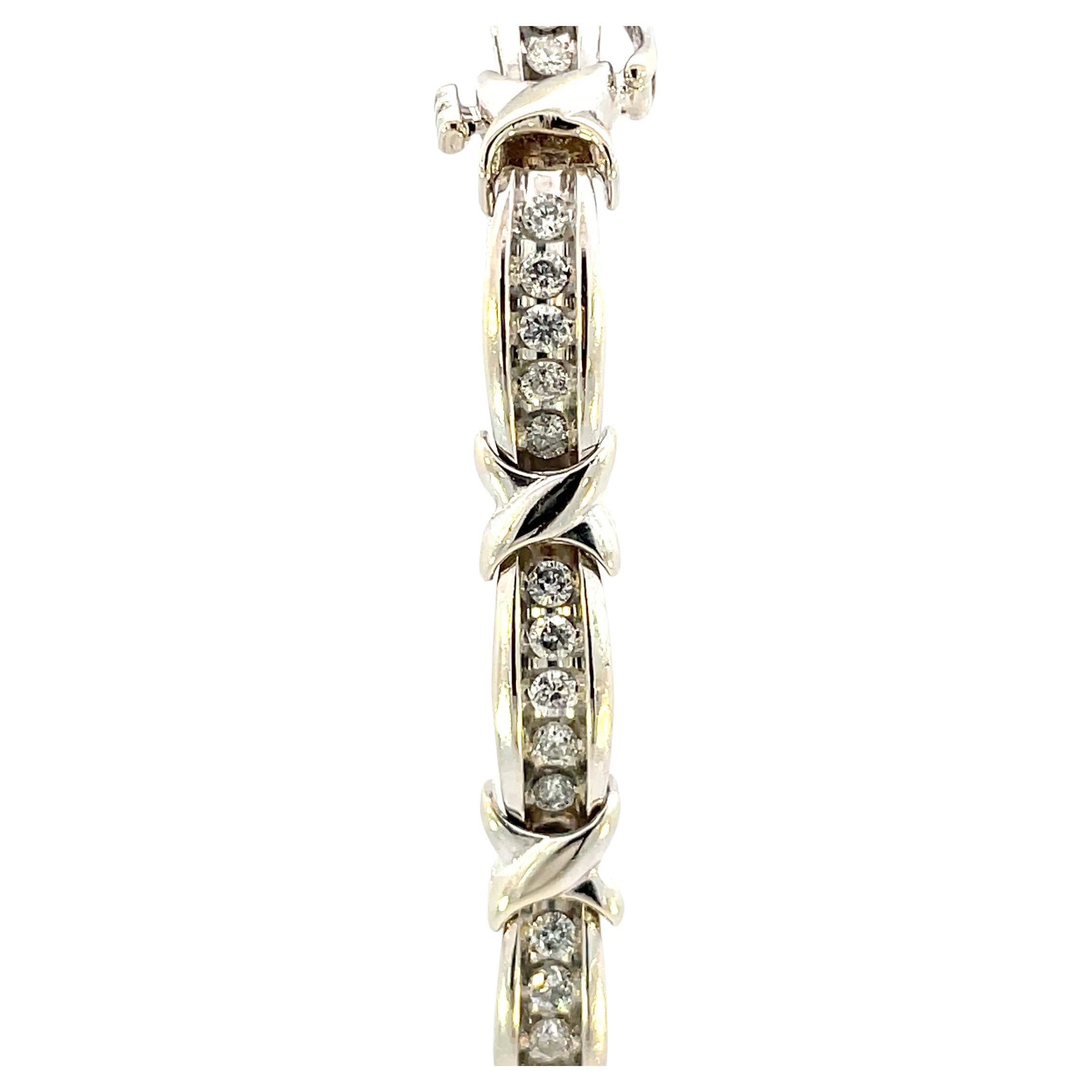 Ce bracelet contemporain en or blanc orné de diamants sur le thème des X et des O est absolument magnifique. Chaque section du bracelet contient 5 diamants ronds de taille brillante SI1/SI2 de pureté G/H de couleur, séparés par des maillons en forme