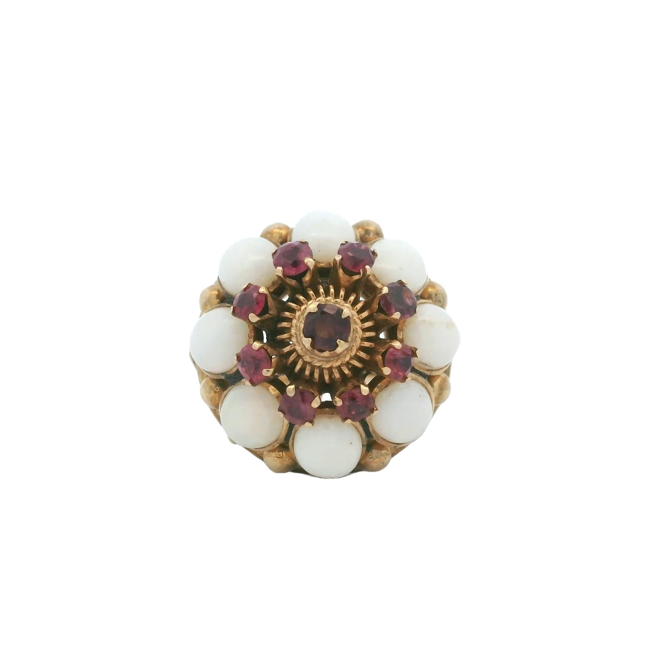 Un sorprendente anello bombe d'epoca realizzato in oro giallo 18 carati, con incastonato un affascinante gruppo di luminosi opali cabochon e vividi rubini. Il centro presenta un singolo rubino circondato da un alone di altri rubini per un totale di