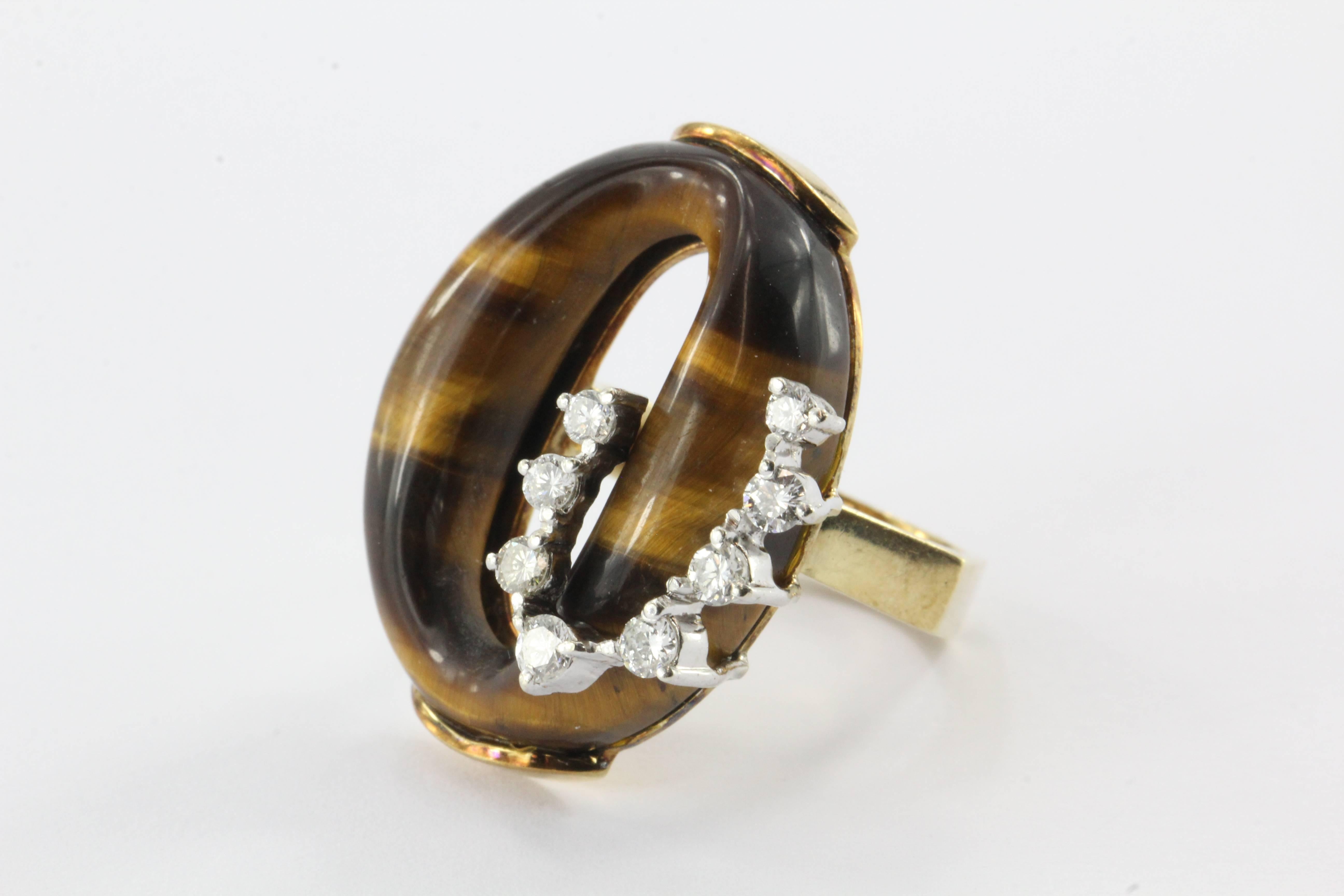 This unusual cocktail ring, reminiscent in design of a coiled snake, features an oval tigers eye mounted on an 18k gold hexagonal ring and topped with diamonds.

The 8 diamonds are F-H in color and vs1 in clarity.

CTW is .4

Size 5

Weighs