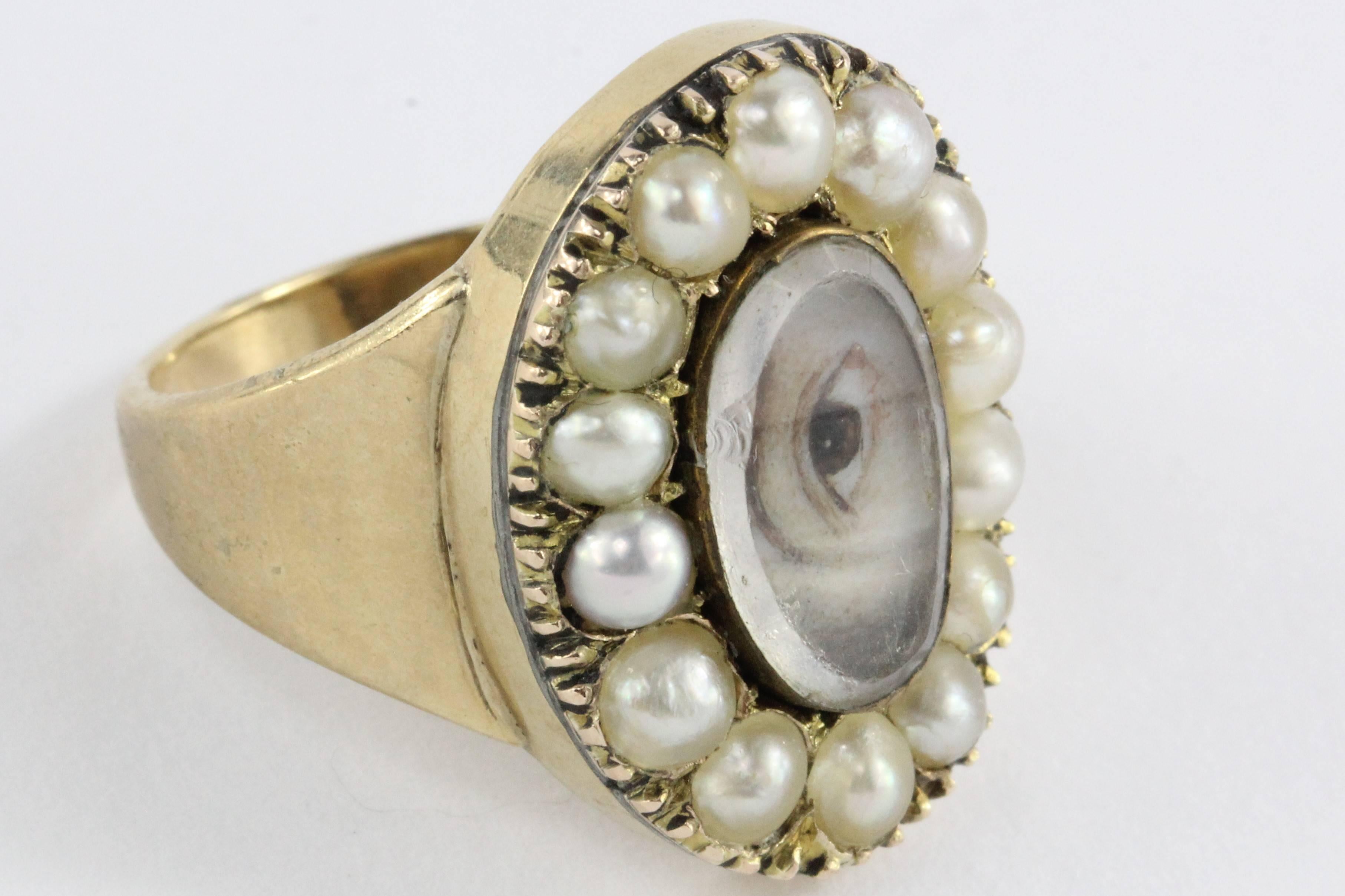 Miniature portrait painted in watercolor portraying a male eye. The lover’s eye is set with beveled crystal to protect the watercolor painting and is framed by natural pearls set in 9K gold. The back of the ring reads "In memory of  RY HORATIO