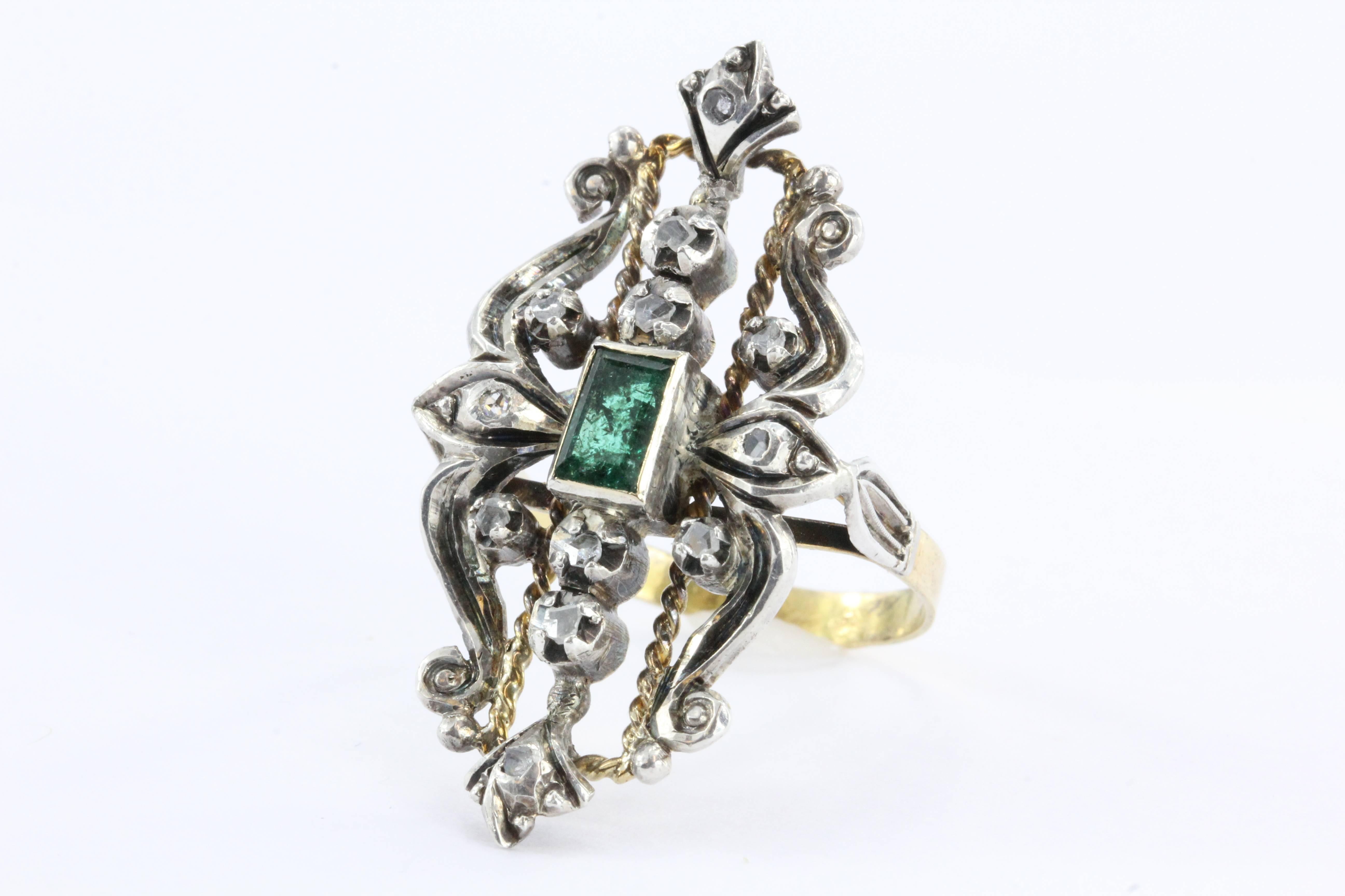Antique 19Kt Gold & Silver Ring from the 19th century. This intricate and elaborate piece of art is set with about .30 carats of genuine rose cut diamonds. The center emerald is about .32 carat and emerald cut. The piece is entirely hand made and in
