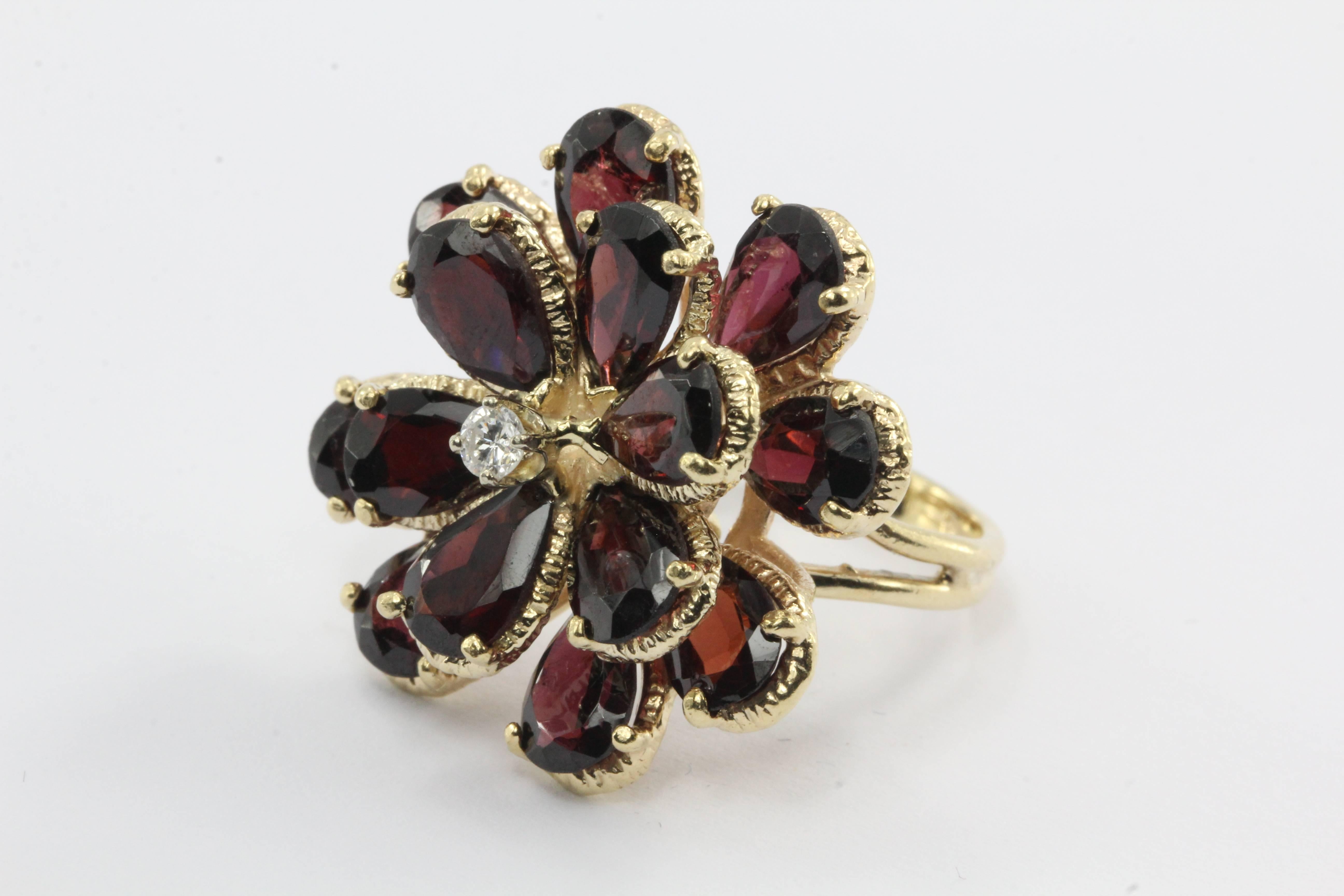 A retro floral garnet & diamond ring in 14k yellow gold circa 1950. This gorgeous vintage ring holds a stunning array of deep rich pear shaped garnets. There are 14 garnet petals in total. The stones are each approximately 8 MM in length and 5 MM in