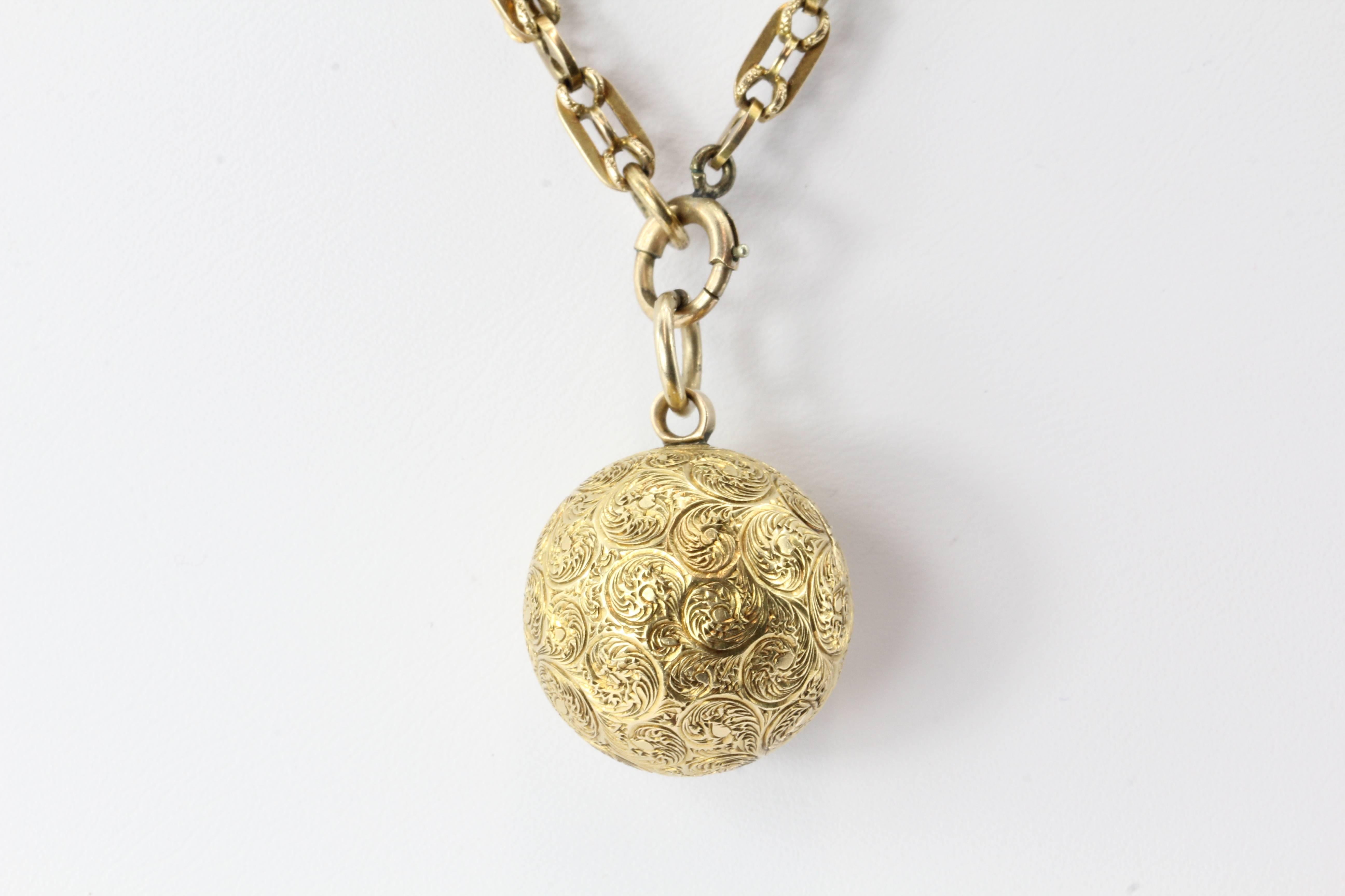 Victorian 18K Gold Ball Locket Pendant on 14K Gold Chain. The piece is in excellent estate condition and ready to wear. The ball locket pendant has a hand chased design on it and it is engraved "Carrie" on the outside. The inside is