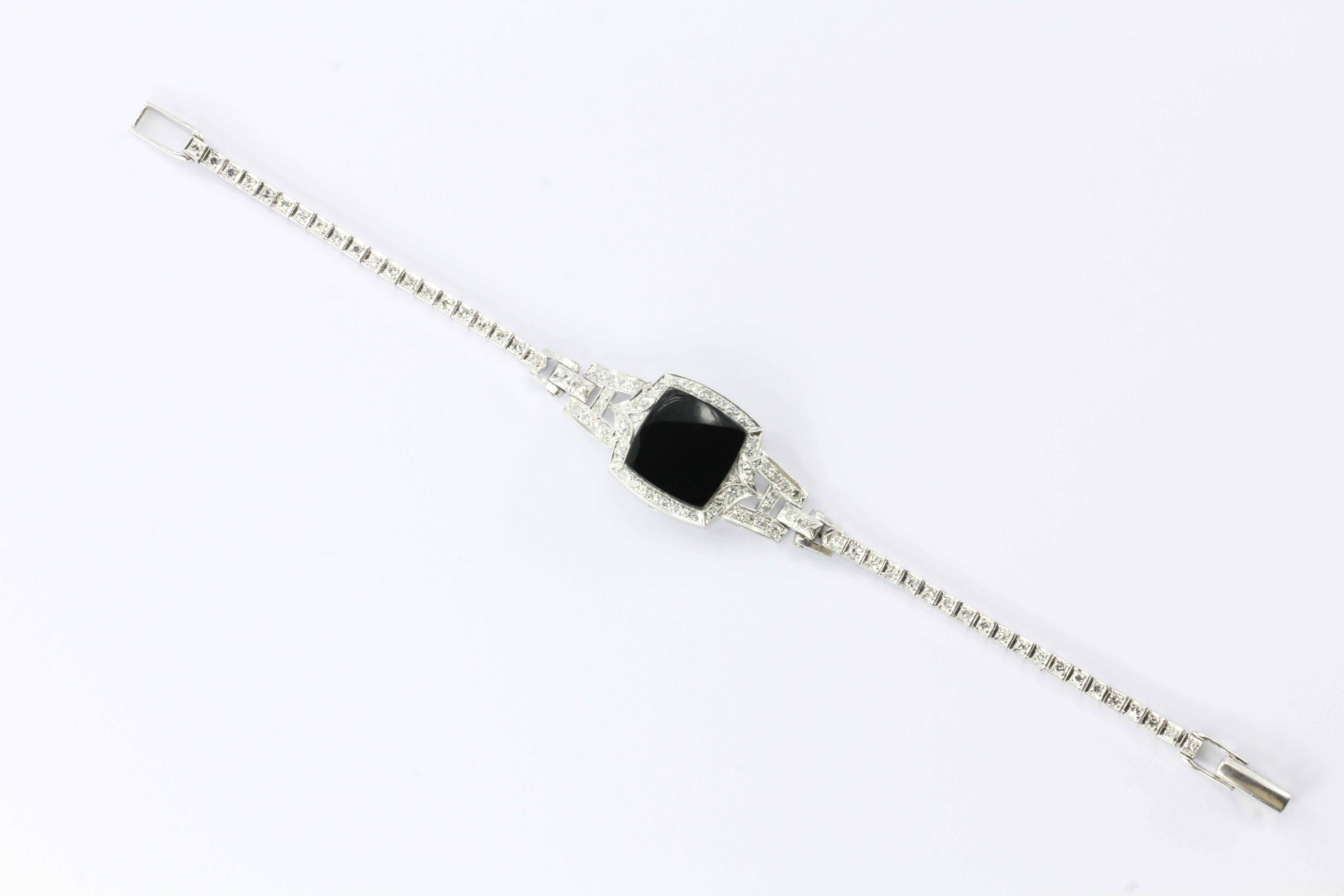 This magnificent and glamorous platinum case, 14k white gold band & diamond bracelet started life as a watch. The broken movement was removed and black onyx was fit in its place. There is approximately 1 carat total of single cut diamonds set in the