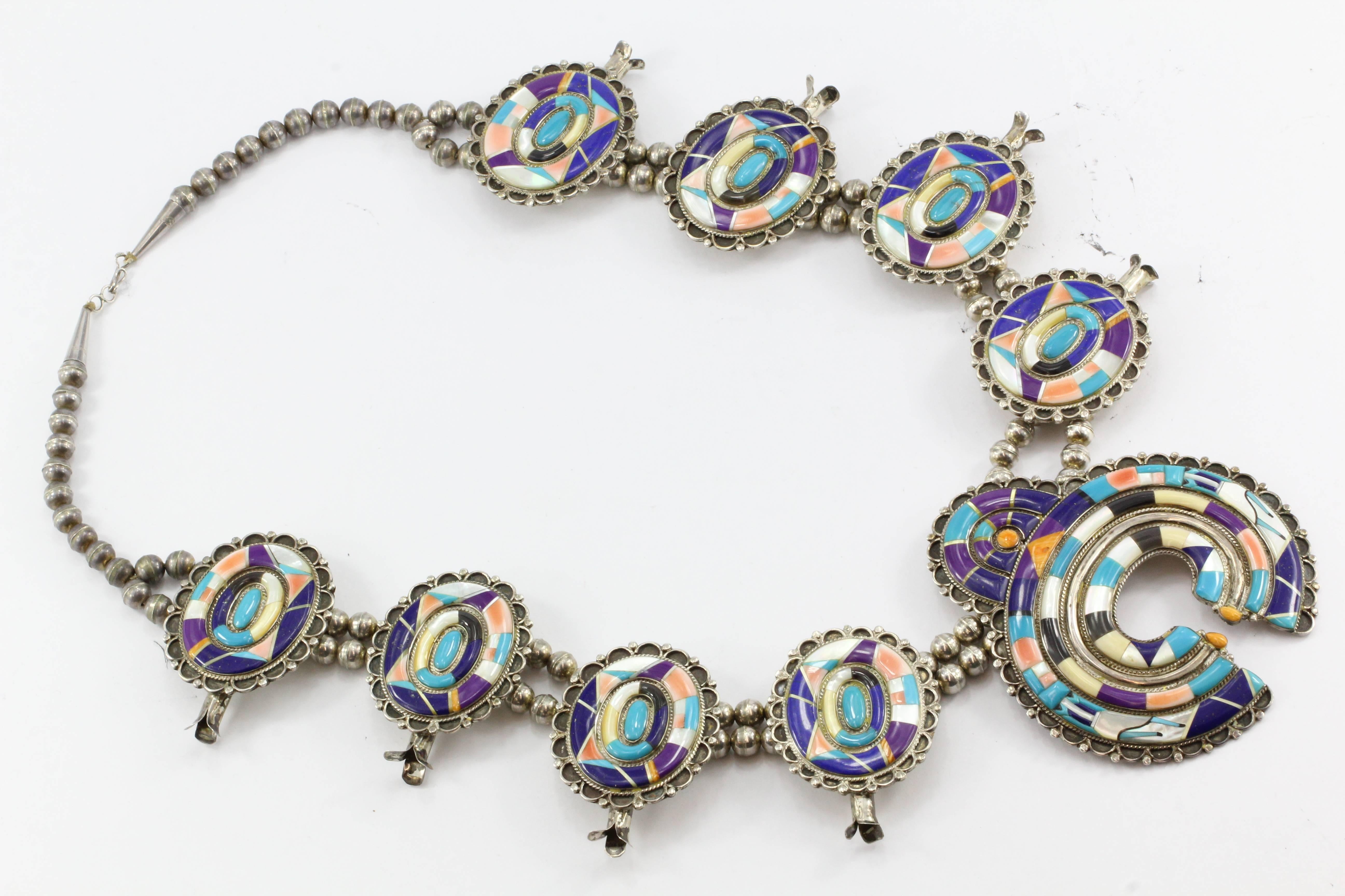 Zuni Silver Snake Rainbow Dance Inlaid Sterling Silver Squash Blossom Necklace

The necklace is in excellent estate condition and ready to wear. It is signed "Rainbow Dance in Apache Canyon Silver Snake STERLING". The piece is made of