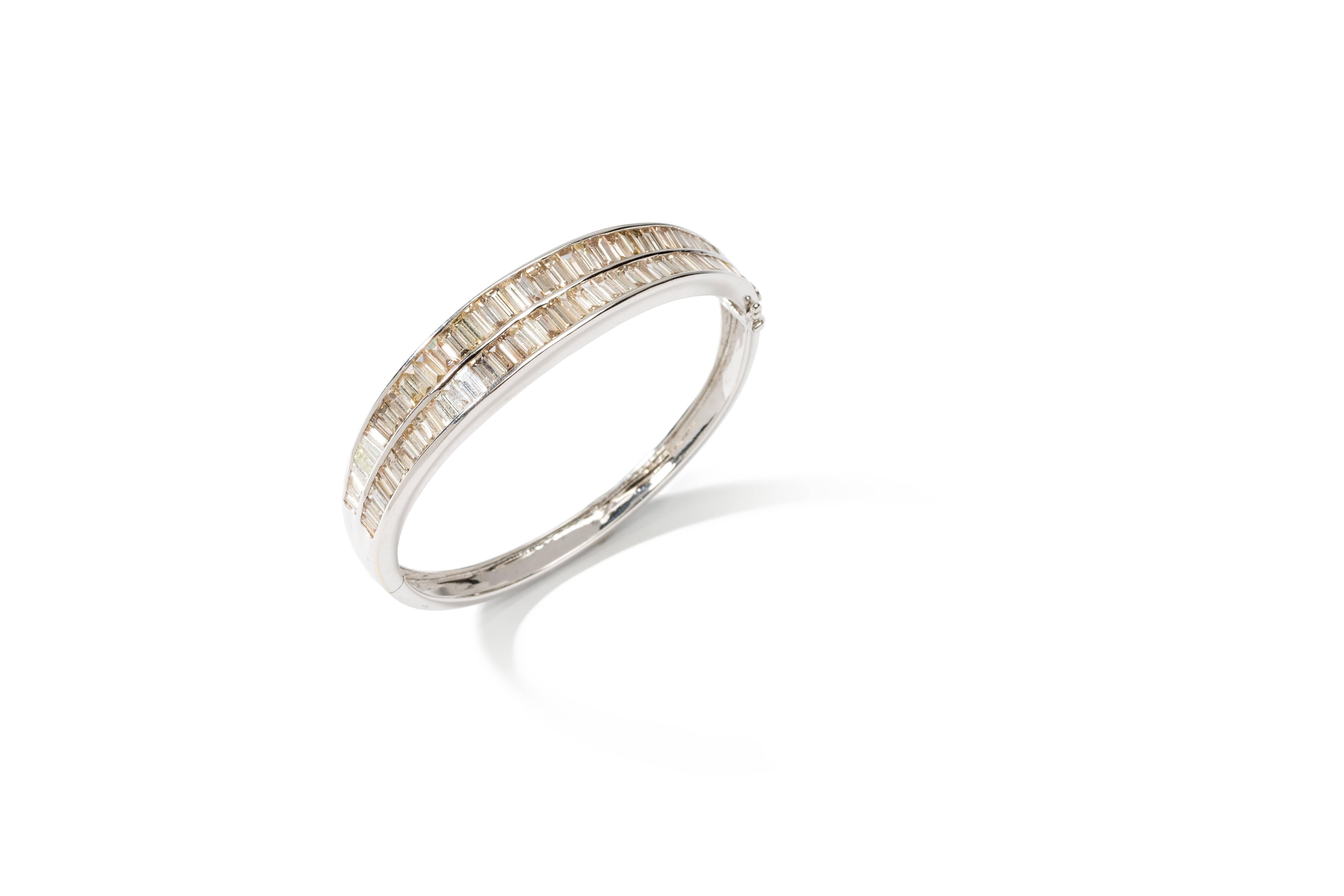 Designed with two rows 77 baguette-cut diamonds weighing 10,81 ct. Mounted in 18 carat white gold. Hallmarked inside: 750, DG in quadrat. Total weight: 29,77 grams. Measurements: 1.97 x 2.28 in ( 5 x 5,8 cm )