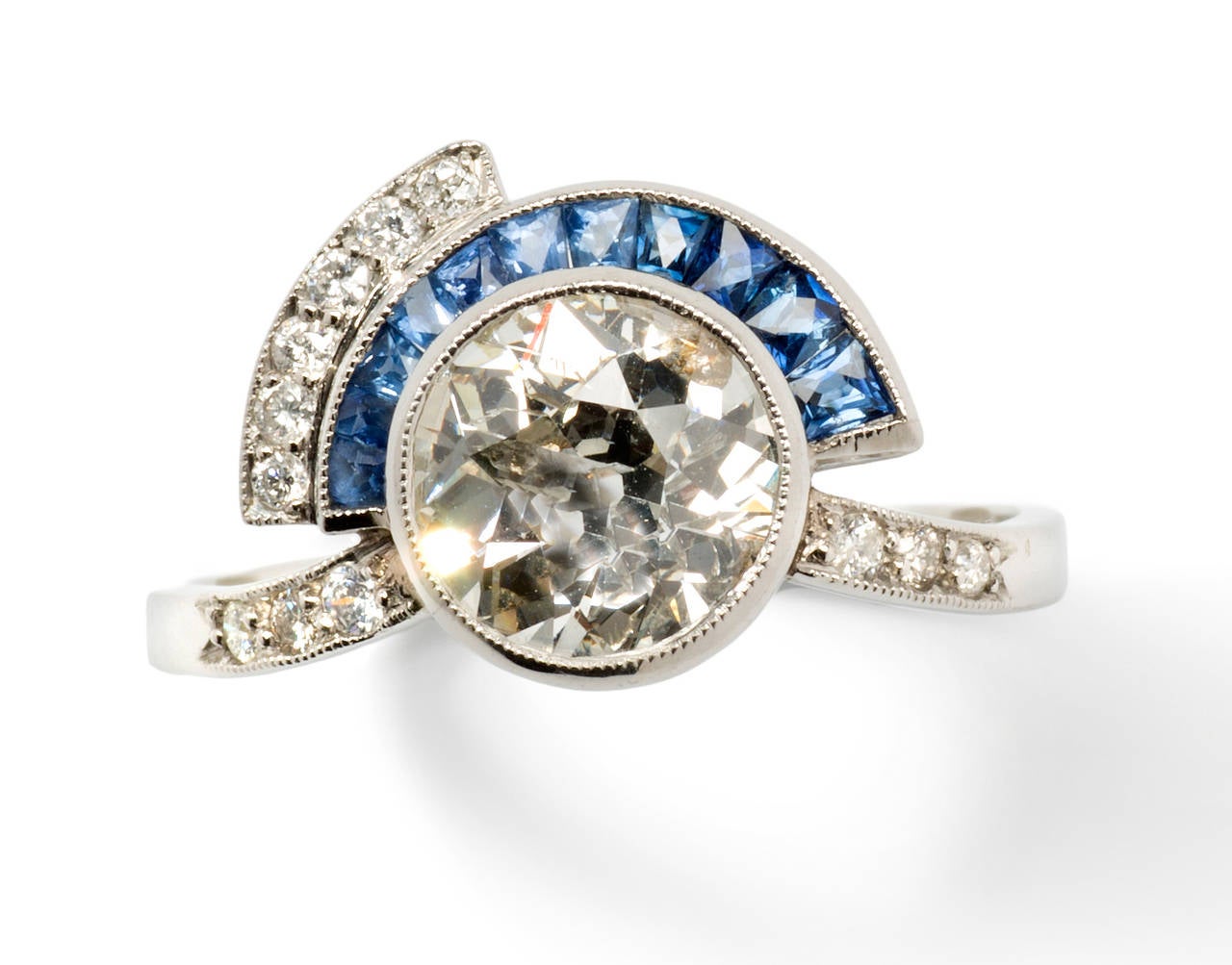 France, ca. 1922. In Art Deco style. Central brilliant-cut diamond weighing circa 2,05 ct, clarity: pique
Accented by 11 sapphires and 12 brilliant-cut small diamonds. Millegrain setting. Mounted in platinum. 
Total weight: 3,88 grams. Ring size: 57