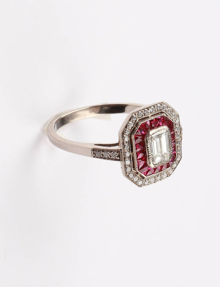 Set with emerald-cut diamond  at the centre weighing 0,44 carats, clarity VS1, color H. Flanked by 18 French-cut rubies weighing 0,98 carats and 36 diamonds weighing 0,20 carats. Mounted in 18K white gold. Millegrain setting. Ring band decorated