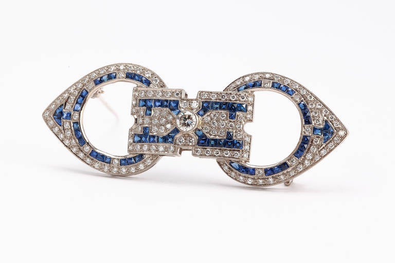 Bow-shaped openwork geometrical set with 141 brilliant-cut diamonds weighing 0,88 cts. Accented by 70 french-cut sapphires weighing 3,8 cts. Mounted in 18 K white gold. Millegrain setting. Hallmarked with the purity 18K on the rear side. 
Total