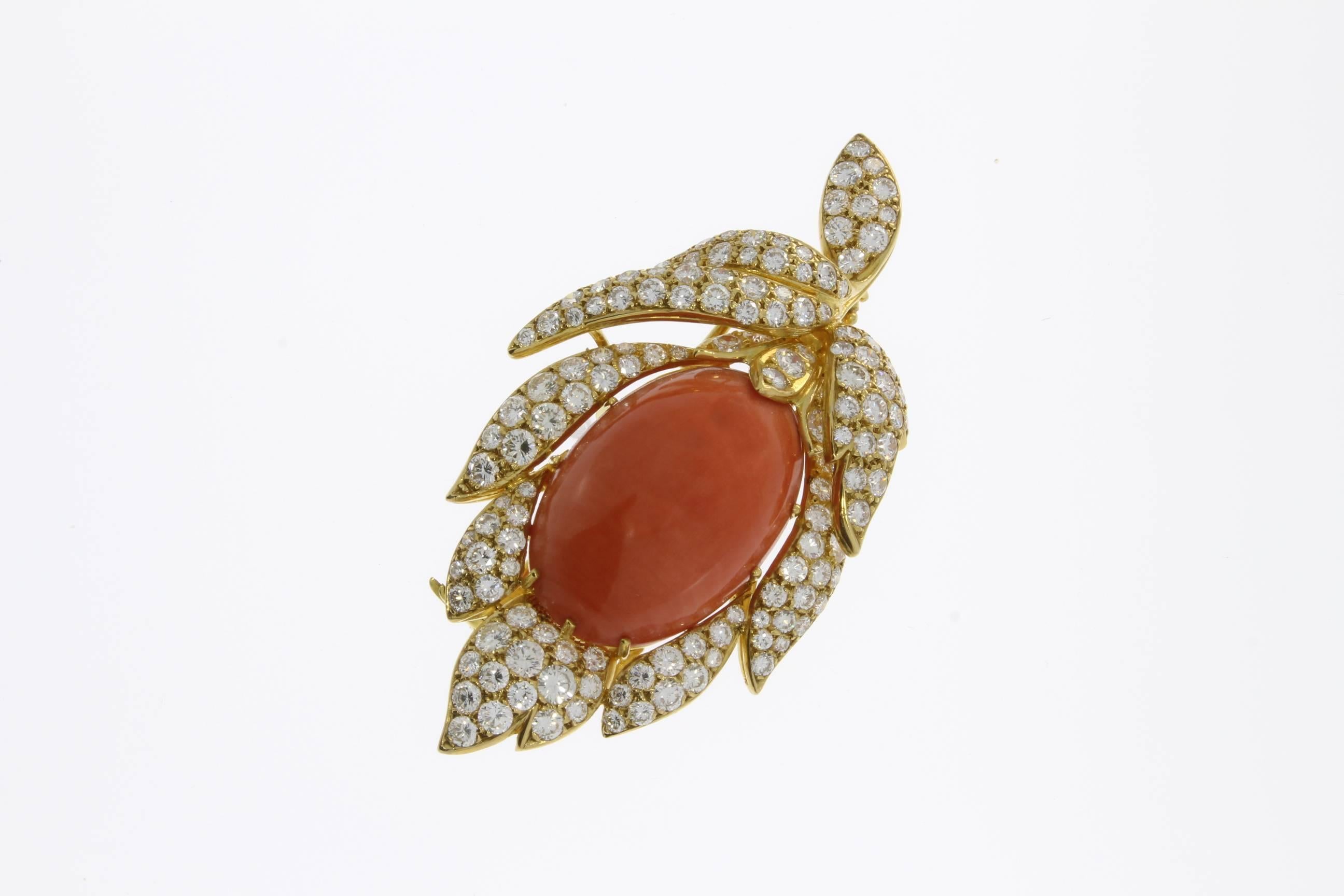 Floral shape brooch/pendant with oval momo coral cabochon in a center. Decorated with 133 brilliant-cut diamonds weighing approximately 10,0 ct. clarity: VS1, color: H ( white ). Pavé setting. Mounted in 18 K yellow gold. 
Total weight: 23,37 g.