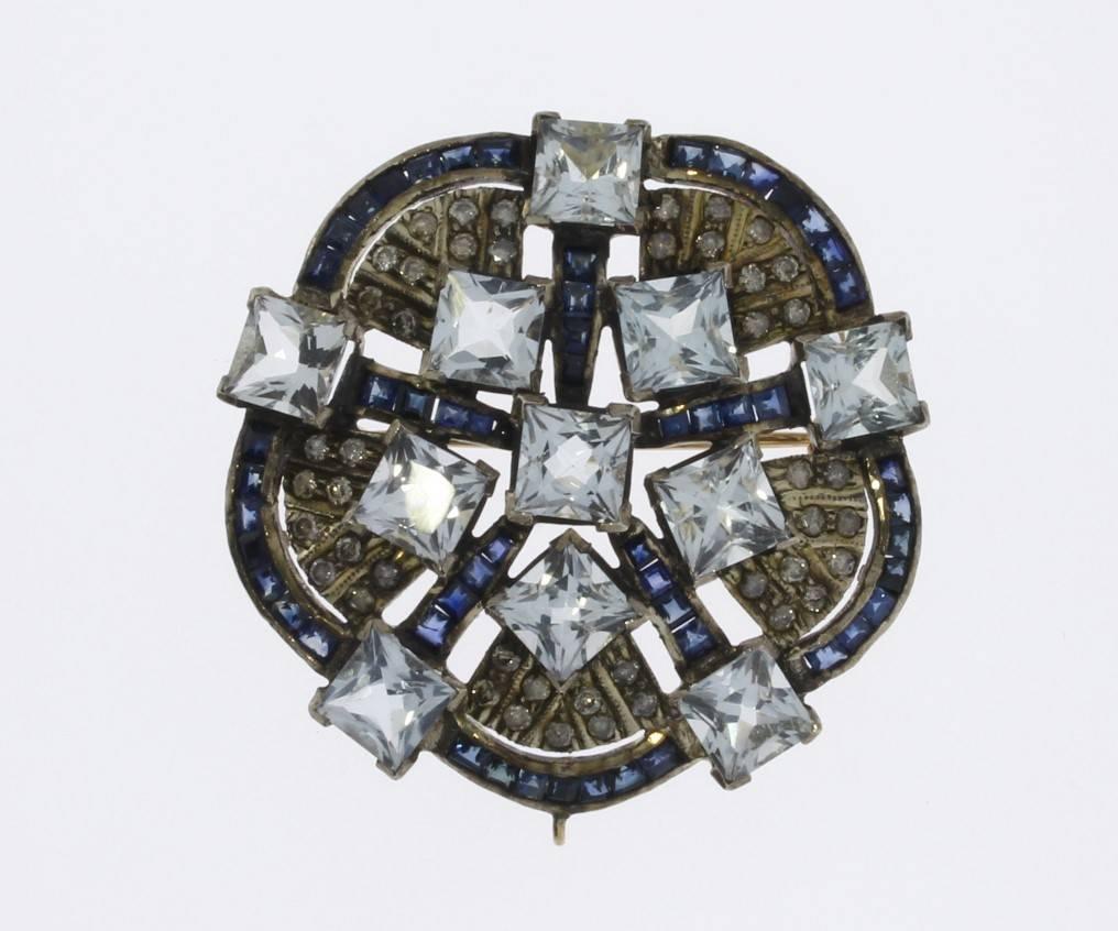 Beautiful floral design, Europe 1940's. With 11 princess-cut aquamarines, framed by 55 sapphires and filled by 45 diamonds weighing ca. 0,45 ct. Mounted in 18K yellow gold in millegrain setting and sterling silver. Total weight: 14,51 g. Diameter: