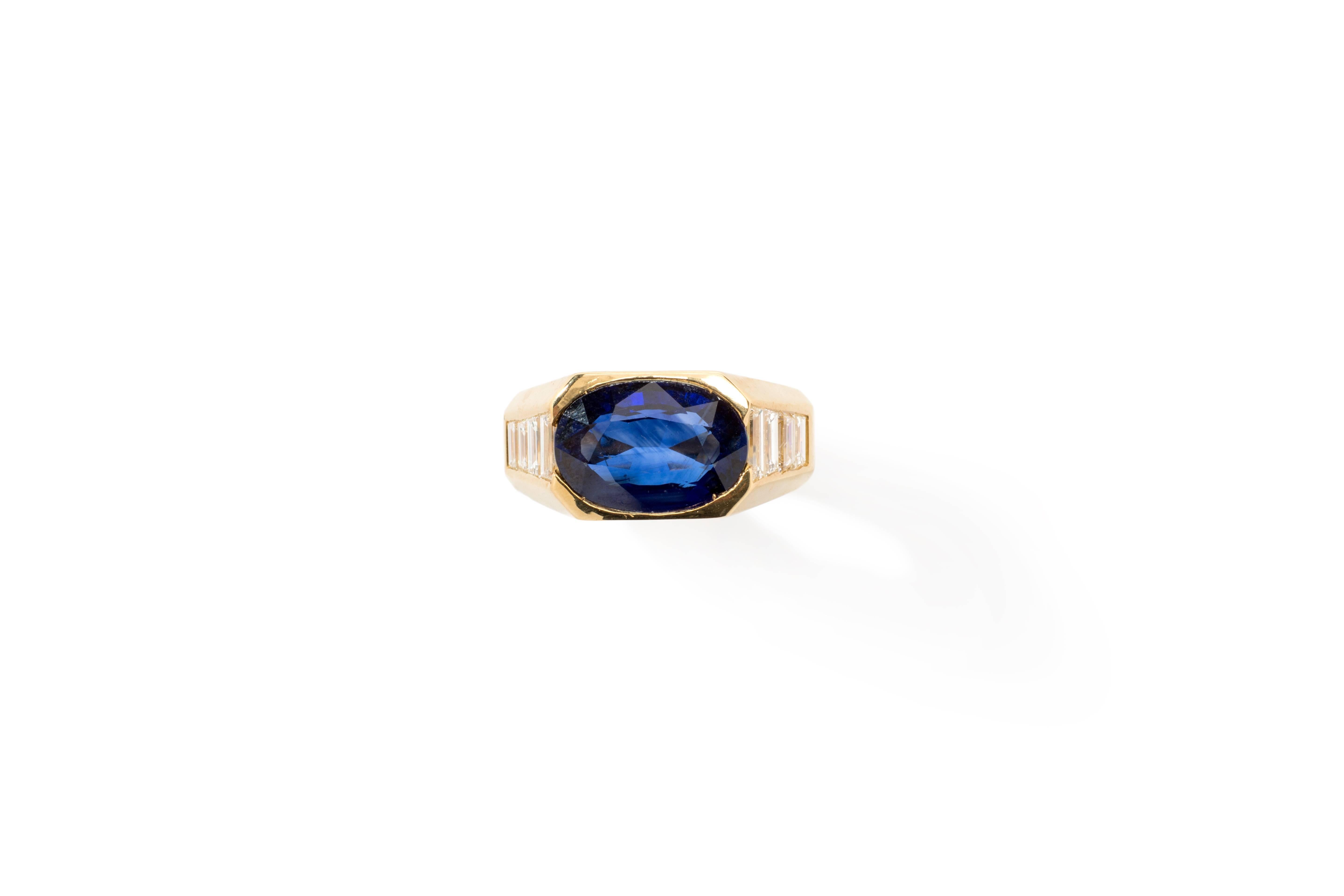 1970's. Set with deep-blue oval shaped sapphire weighing 4,08 ct. 
Accented by 8 baguette-cut diamonds ( totally 0,80 ct.) on a 18K yellow gold band. Total weight: 12,91 g. 
Height: 0.24 in ( 6 mm ). Ring size 50 ( US 5 ) Resizable
