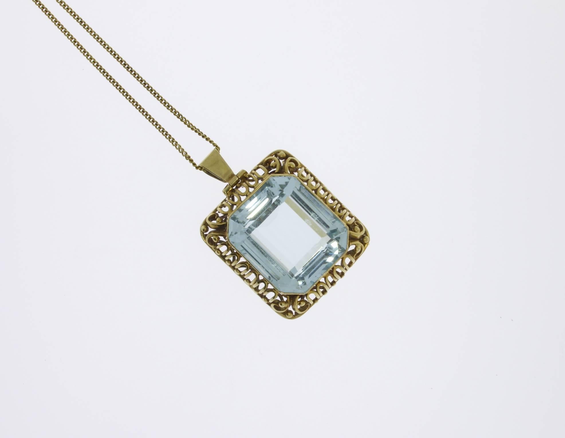 The classic pendant consist of 14 K yellow gold and shows a large emerald-cut aquamarine weighing circa 38 ct. 
On the loop marked with the purity 585.  That can also be worn as a brooch. Total weight: 23,16 g. 
Dimensions of pendant: 1.26 x 1.1 in
