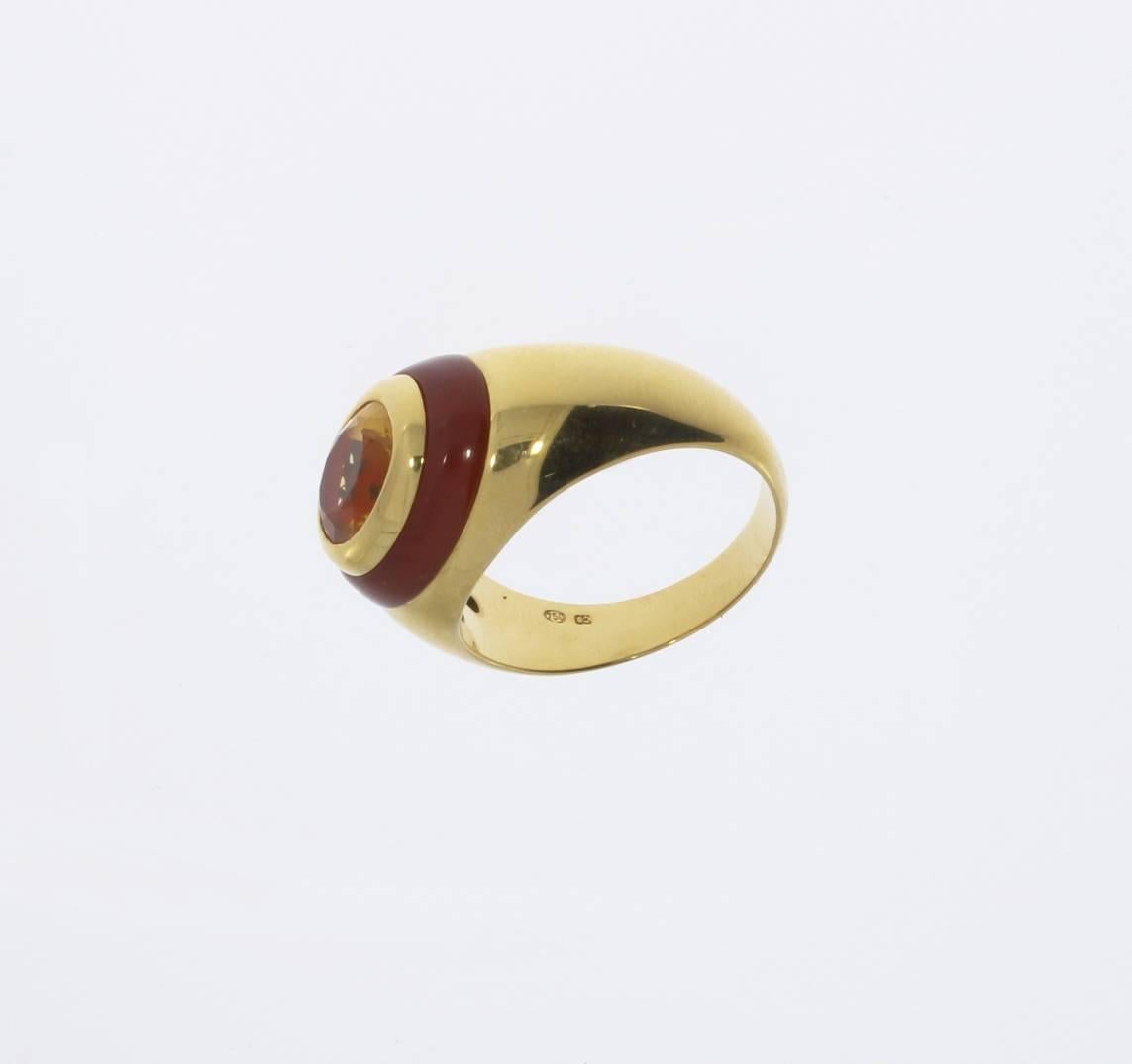 Set with oval shaped citrine in bezel setting edged by carnelian band and mounted in 18 K yellow gold. 
Hallmarked inside with the purity 750 and OE. Total weight: 14,52 g. Height: 0.35 in ( 0,9 cm ) Ring size: 65 ( US 11 ) 

