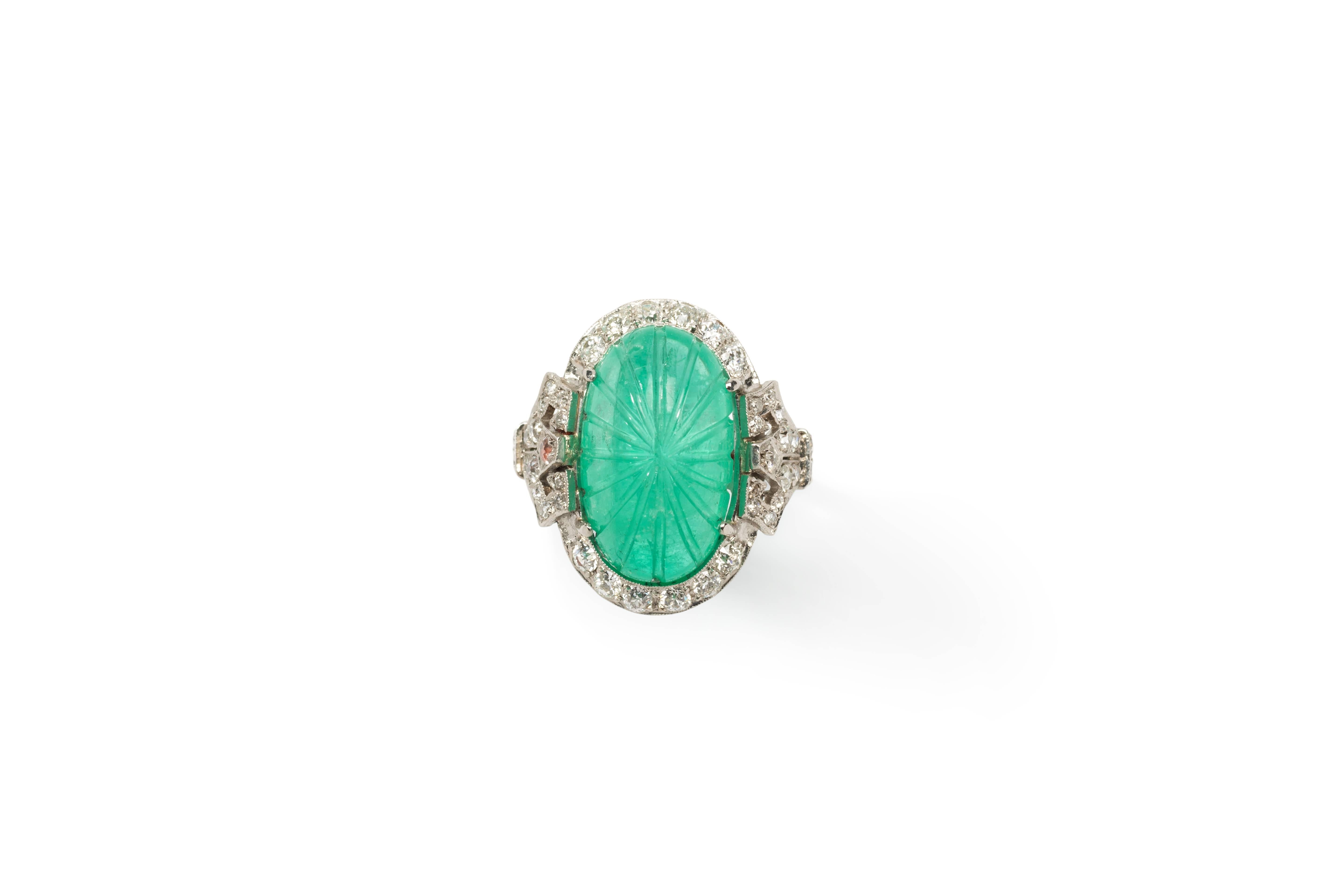 Art Deco ring with carved oval shaped Colombian emerald cabochon weighing 10,12 ct. Surroundet by 42 old-mine-cut diamonds with a total weight of 0,90 ct. clarity VS-SI, color wesselton. Mounted in platinum. Hallmarked inside with the purity 950.