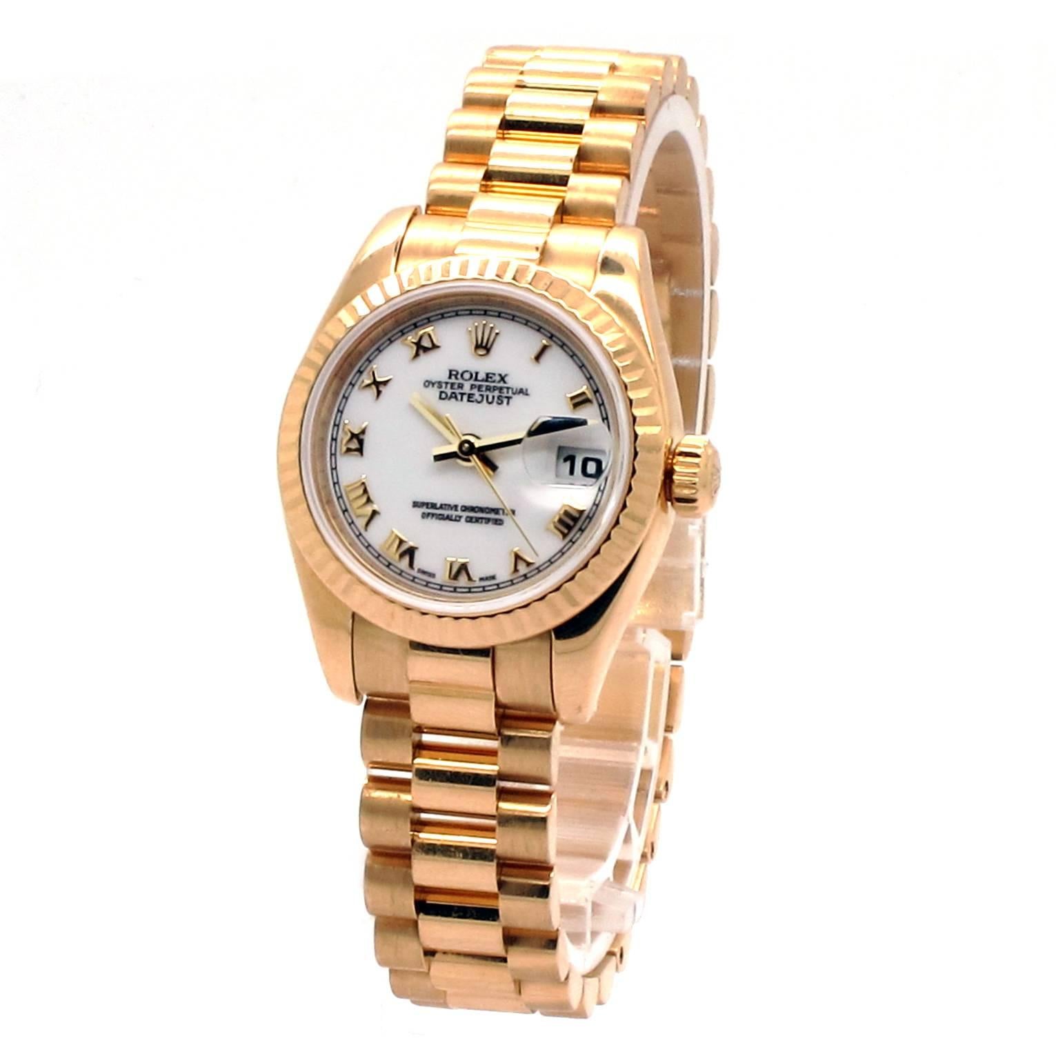 Rolex Datejust Ladies Presidential Watch with a round 26mm 18K yellow gold case with 18K yellow gold fluted bezel. White dial with gold roman numeral hour markers. 18K yellow gold president bracelet with hidden deployment buckle. Screw down crown.