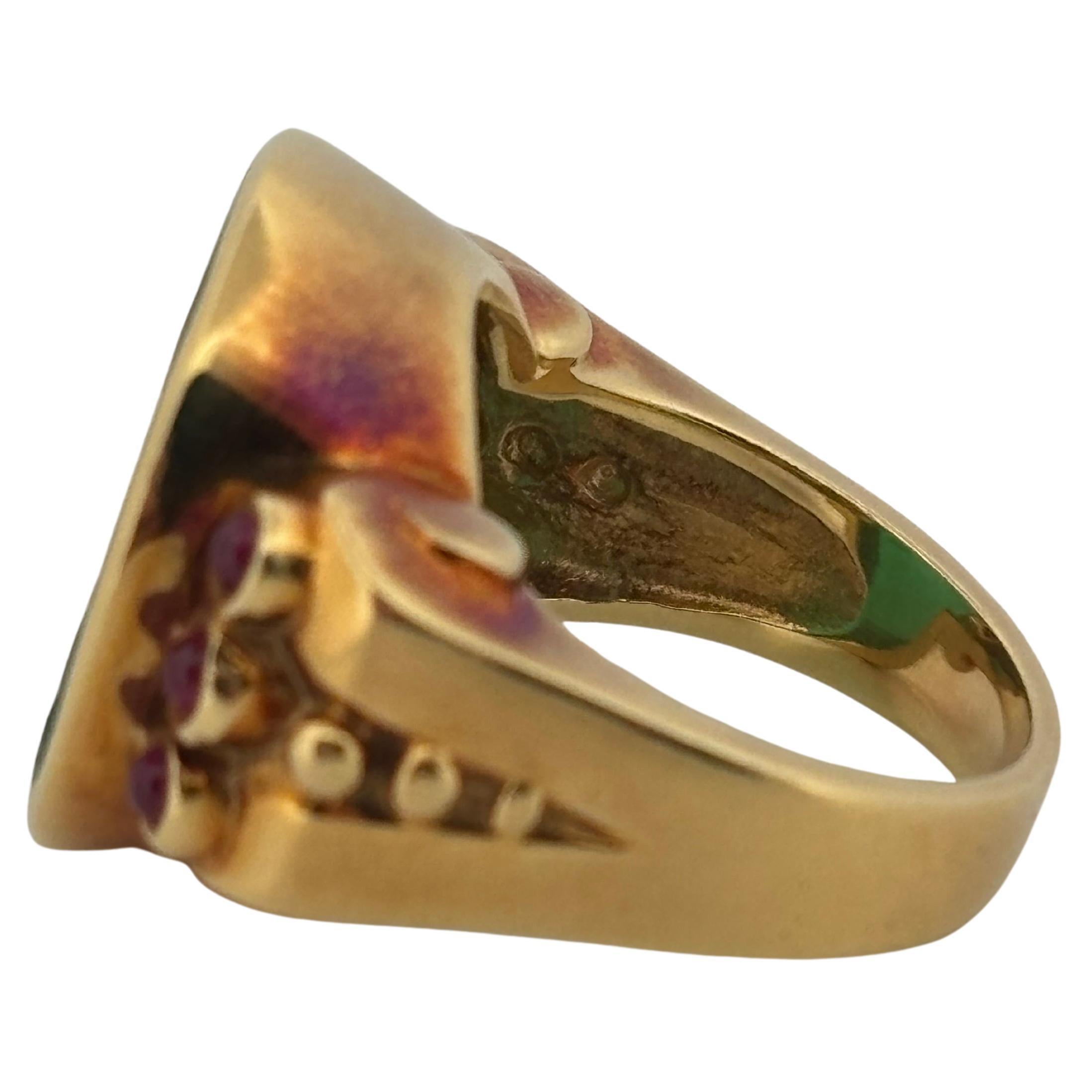 A striking blend of artistry and elegance, this 18k yellow gold ring features a finely carved green agate cameo depicting a classical female profile. The richly saturated agate is accented by six cabochon rubies—three bezel-set on each shoulder—each